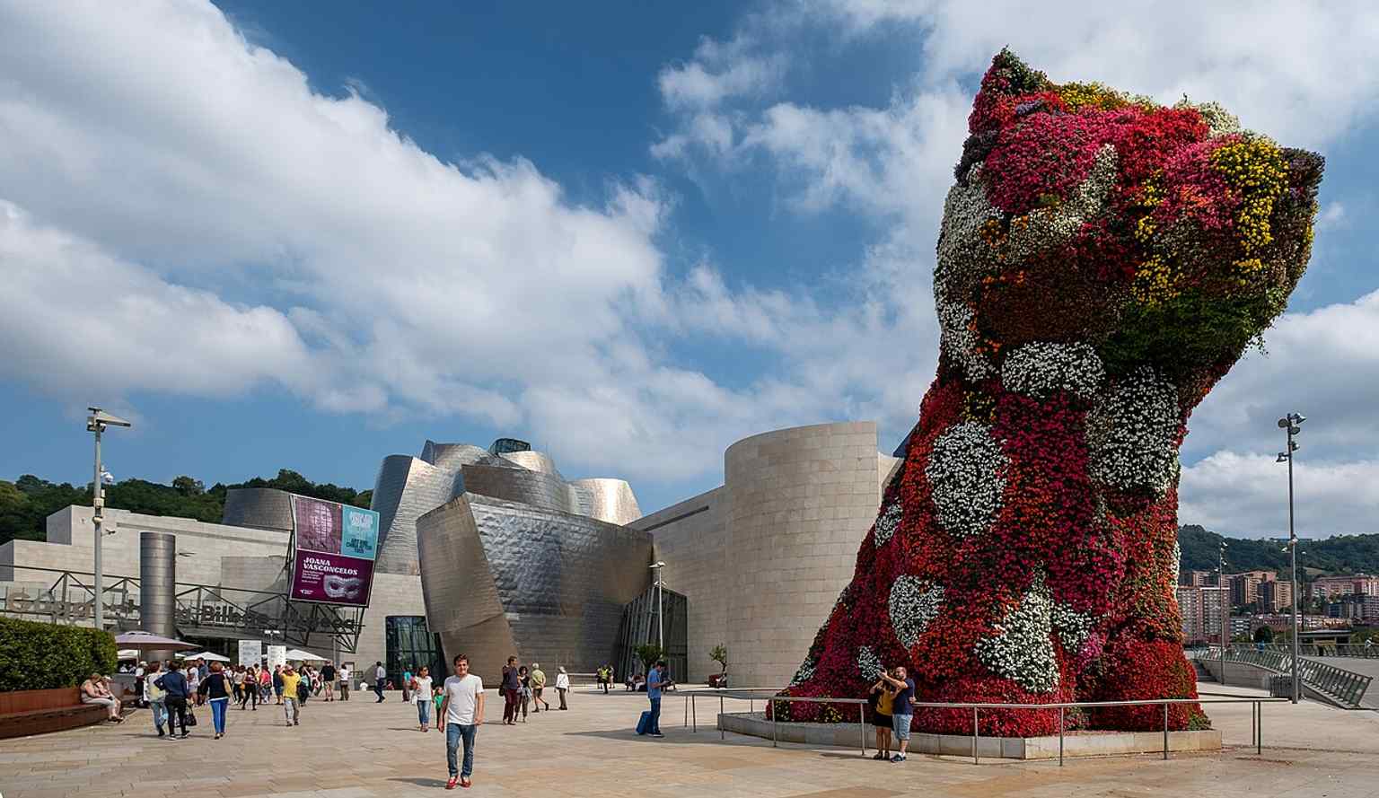 A strong architectural context shot: Puppy in front of the Guggenheim, linking Koons’s bright sculpture with Bilbao’s museum icon.