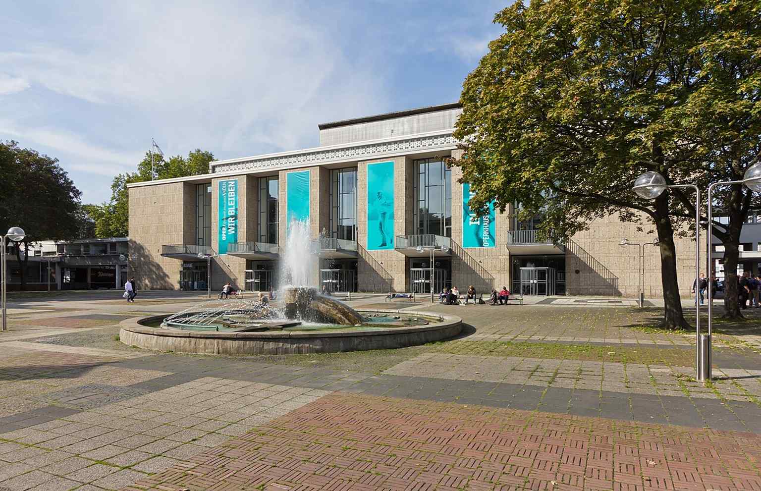 Der Offenbachplatz verfügt über diesen Mosaikbrunnen, entworfen von Jürgen Hans Grümmer, der Fragmente der Kaiser-Wilhelm-Gedächtniskirche und der Yacht von Aristoteles Onassis einbezieht.
