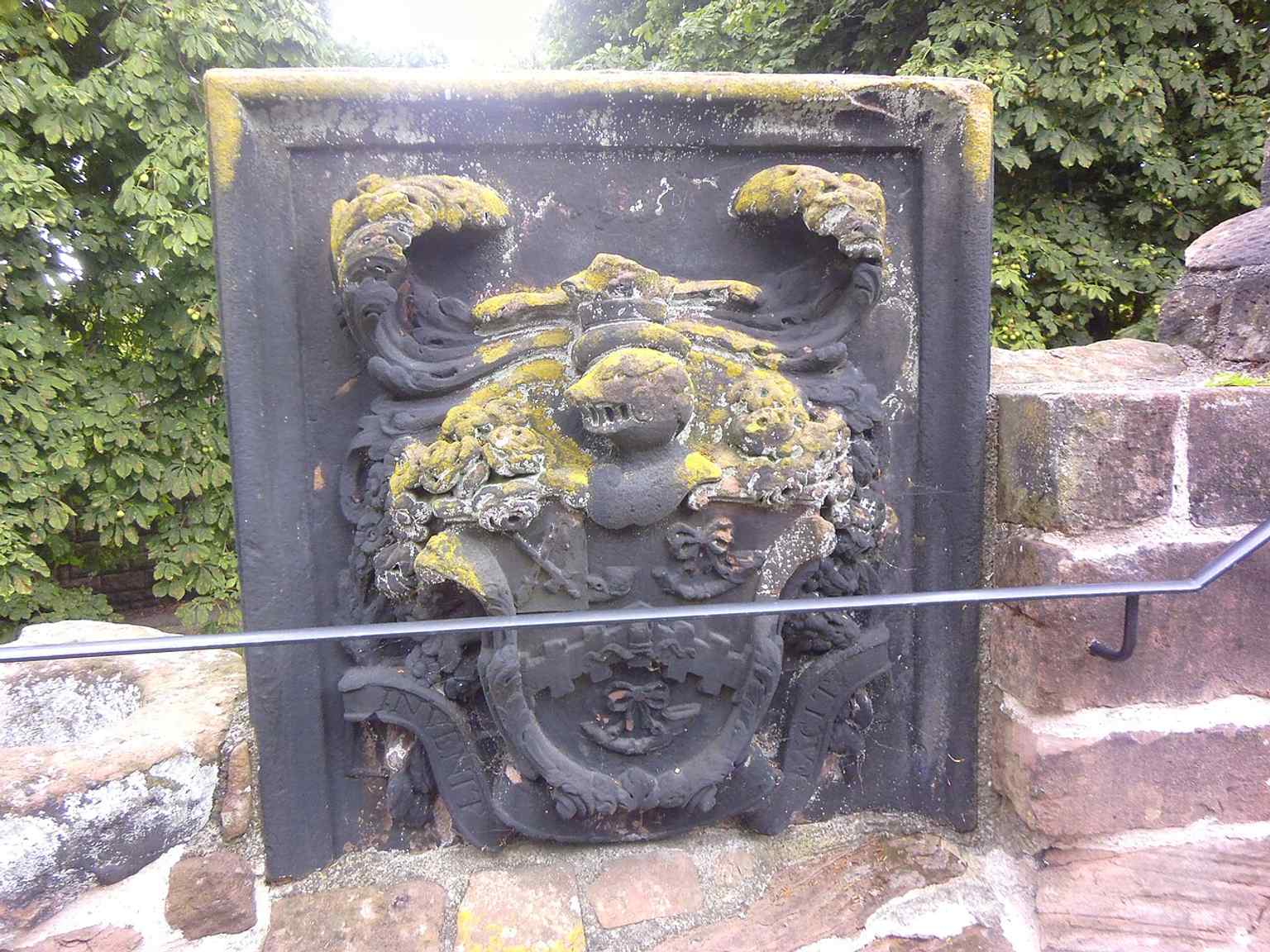 A coat of arms on the spur wall, a decorative survival on the medieval stonework linking the two towers.