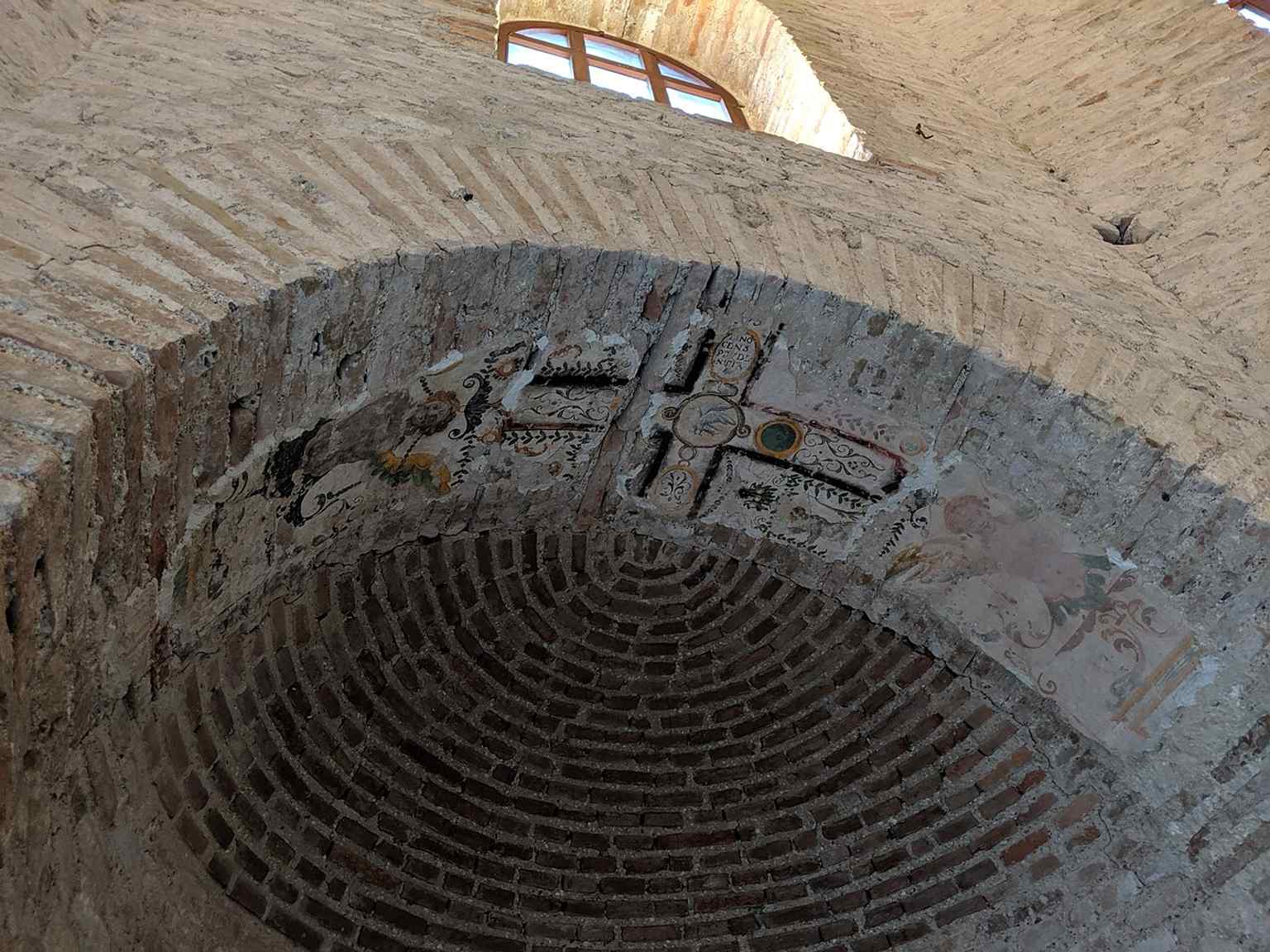 Inside the octagonal space, where the baptistery’s stripped walls make the surviving dome mosaic feel even more prominent.
