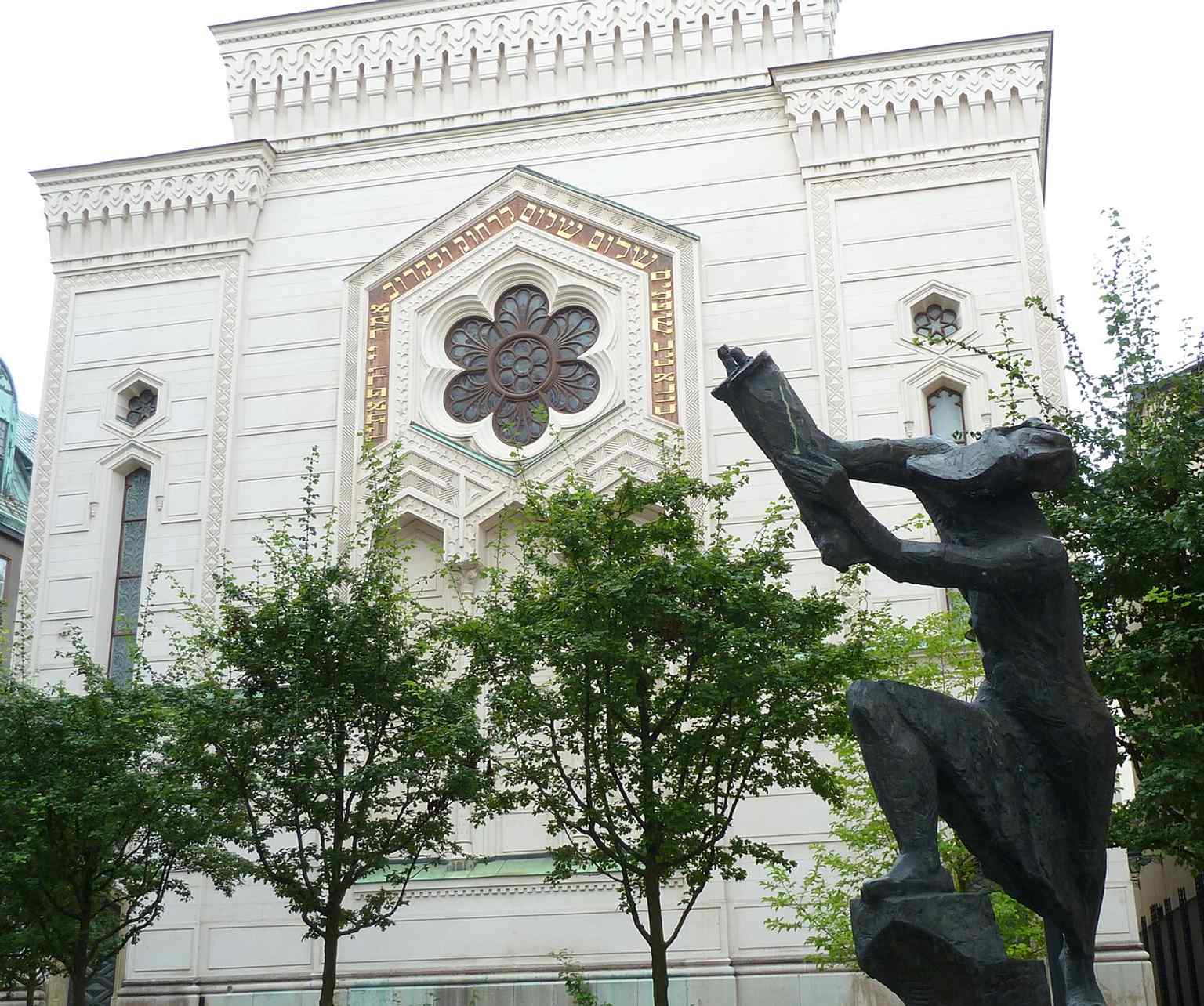 The Great Synagogue's ornate Moorish Revival architecture stands beside Willy Gordon's 1945 sculpture Flykten med Toran (Escape with the Torah), symbolizing refugees clutching a Torah scroll.