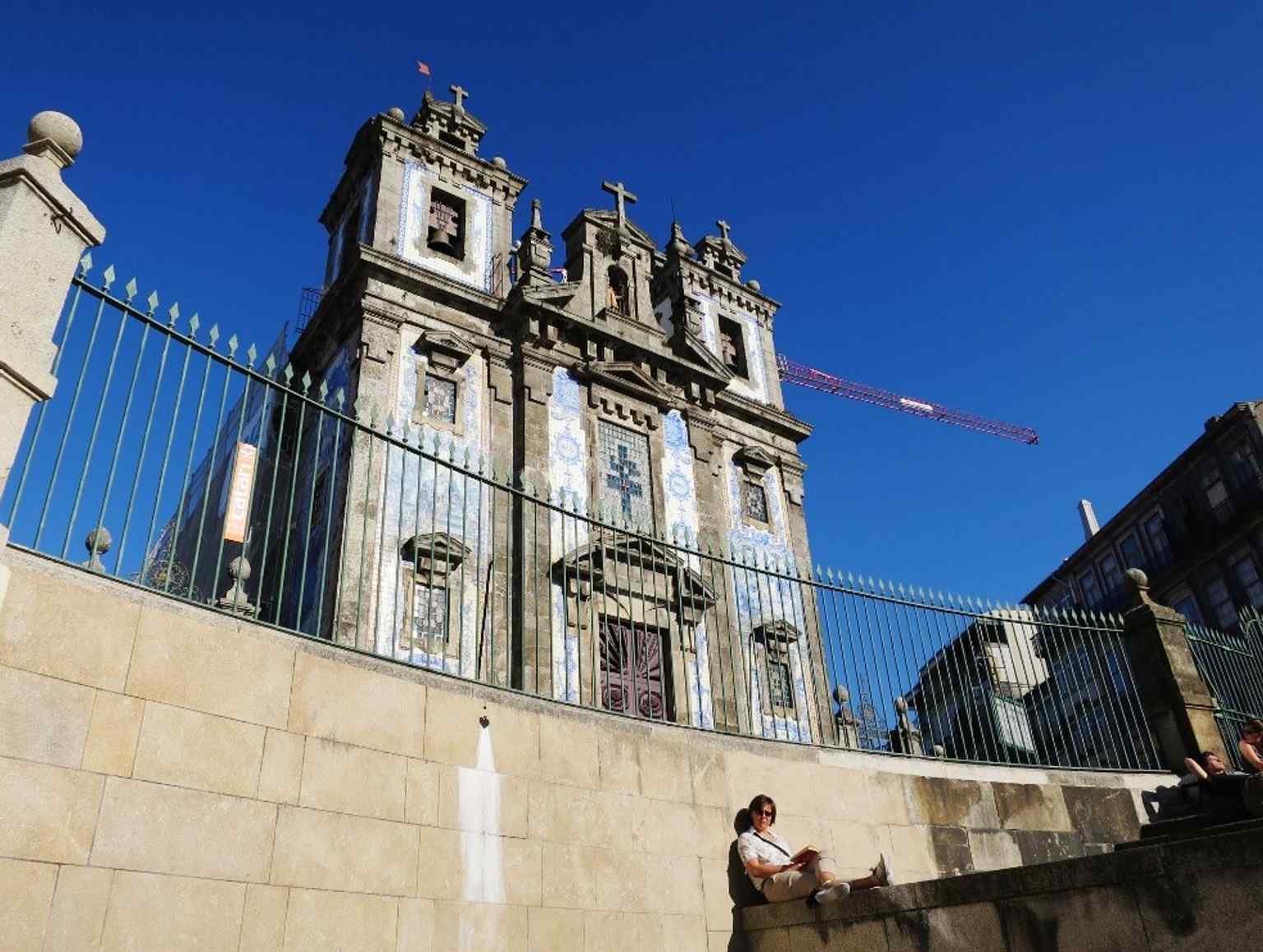 The main façade in a clear, centered view, showing the twin bell towers and the plain granite structure behind the tilework.