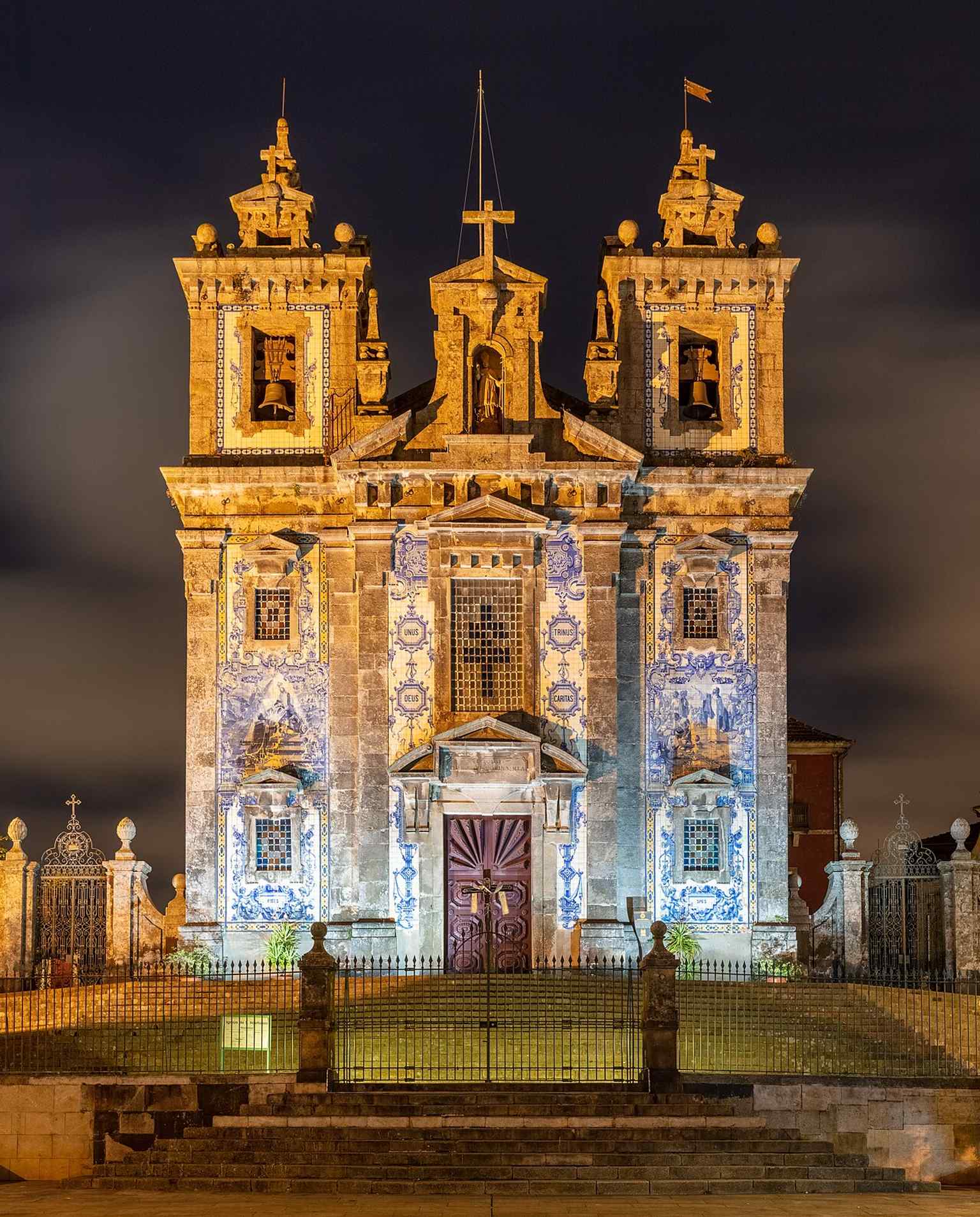 Night photography emphasizes the 1932 azulejo façade and the church’s dramatic presence after dark in central Porto.