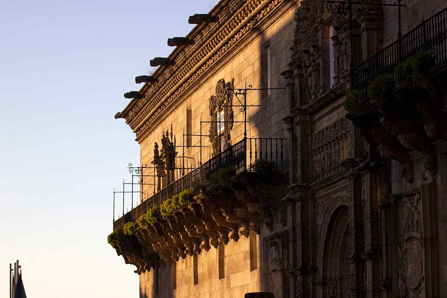 This ornate Baroque balcony was added to the Plateresque façade in 1678 by Frei Tomás Alonso, featuring exuberant vegetal decoration on its large corbels.