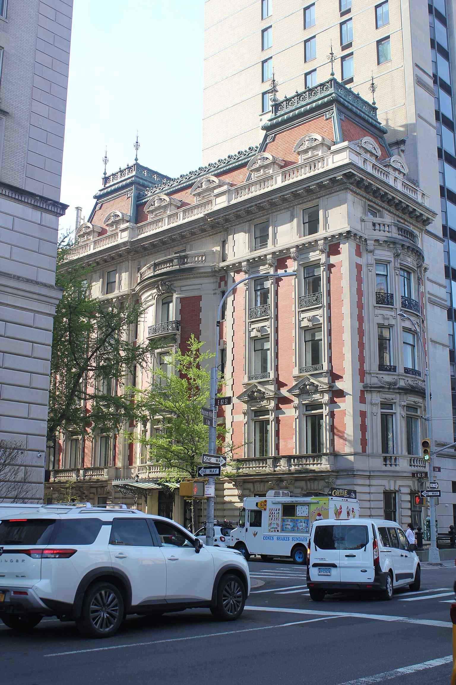 The ornate main entrance on 82nd Street, with its metal-and-glass marquee and wrought-iron doors, serves as the primary entry point to the mansion.