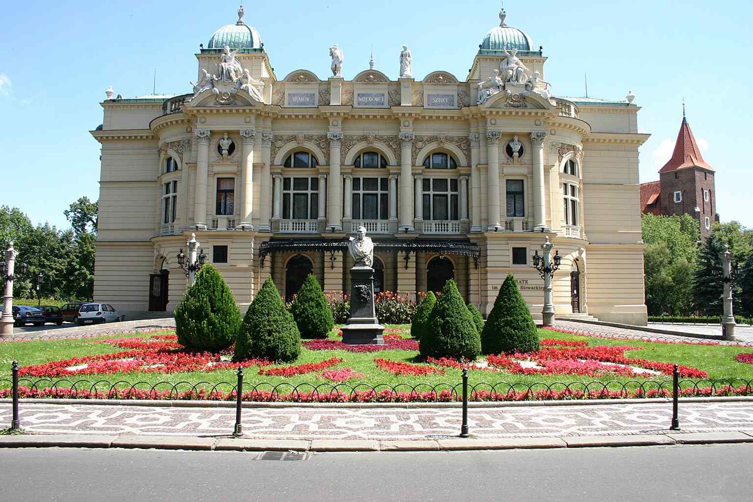 A wider composition pairing the Fredro monument with the theatre, echoing the monuments and literary culture that frame the building.