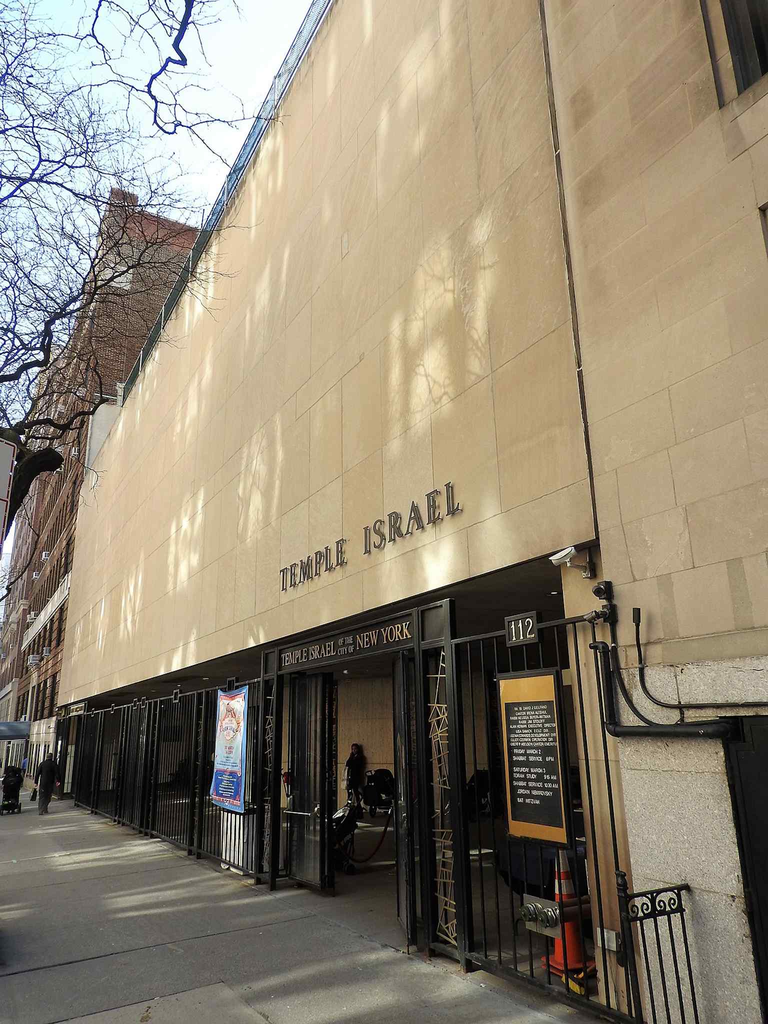 This view highlights the distinctive 100-foot-wide, windowless limestone facade of the current Brutalist synagogue, designed to create a sense of sanctuary.