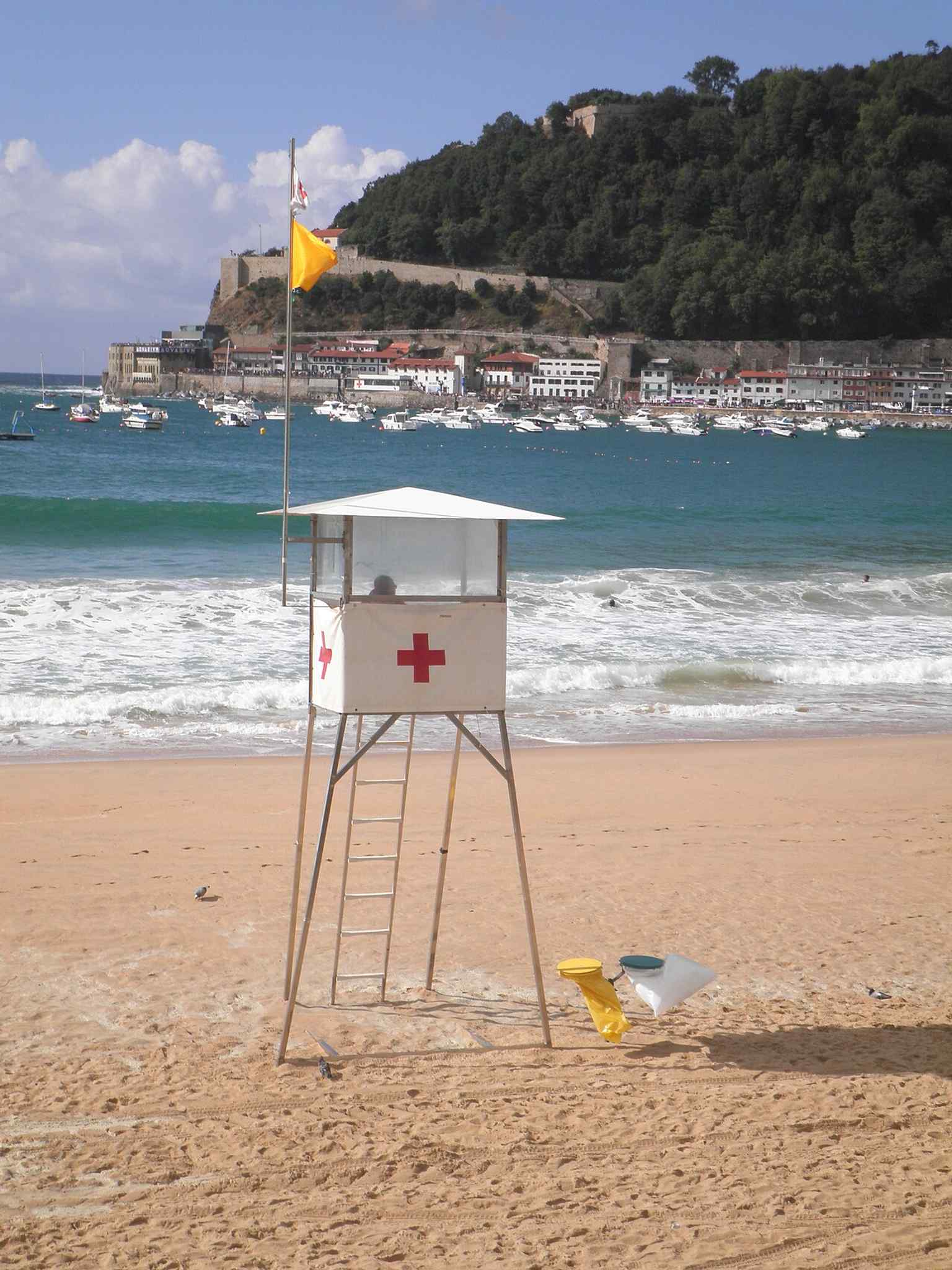A yellow caution flag on La Concha Beach, a practical reminder that this popular urban beach is closely shaped by sea conditions and tides.