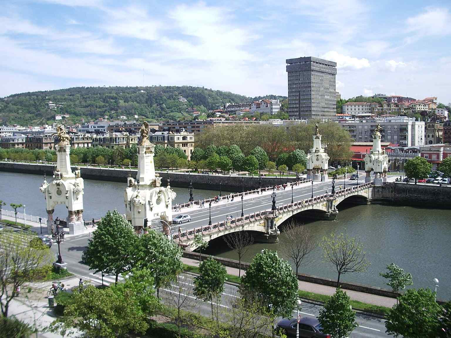 A clear daytime view of María Cristina Bridge with the Atotxa tower nearby, showing its role in the city’s riverfront landscape.