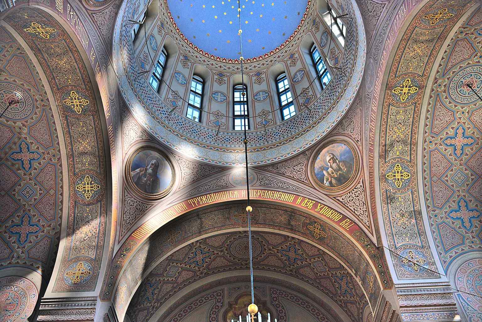 Inside the cathedral, the vaulted Orthodox space and painted ceiling show the Byzantine tradition that contrasts with its rugged red-brick exterior.