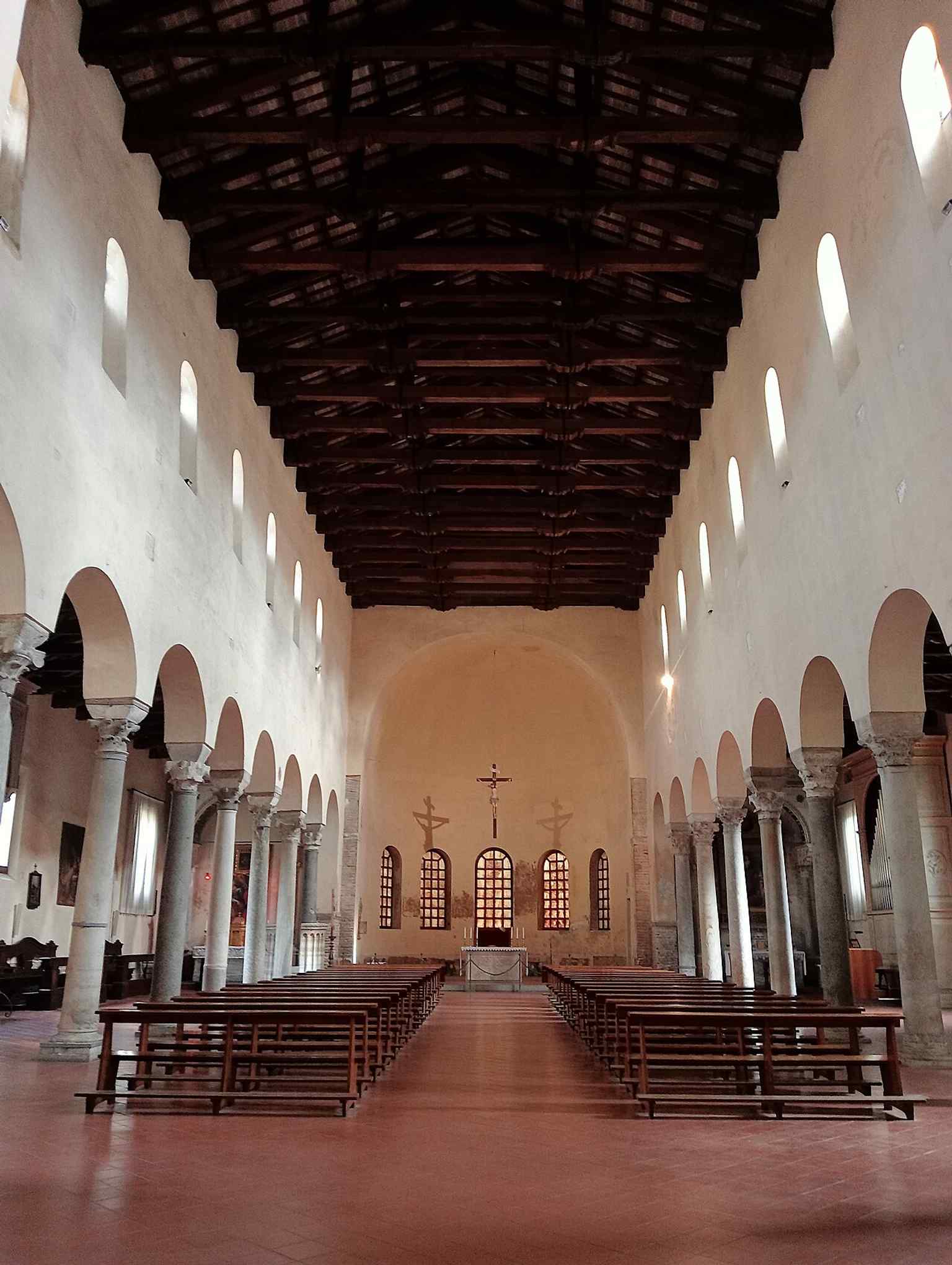 A view inside the basilica’s three-nave interior, where restored paleochristian forms and reused ancient columns reflect the 20th-century restorations.