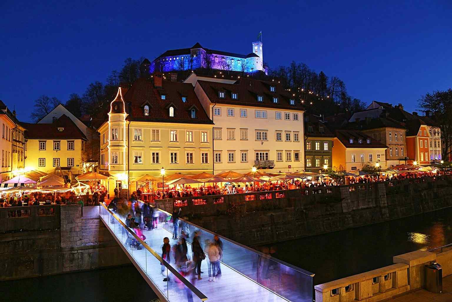 The modern Fish Bridge, seen here glowing at night, connects Kongresni trg with Stara Ljubljana, a link that urbanists like Maks Fabiani foresaw as early as 1895.