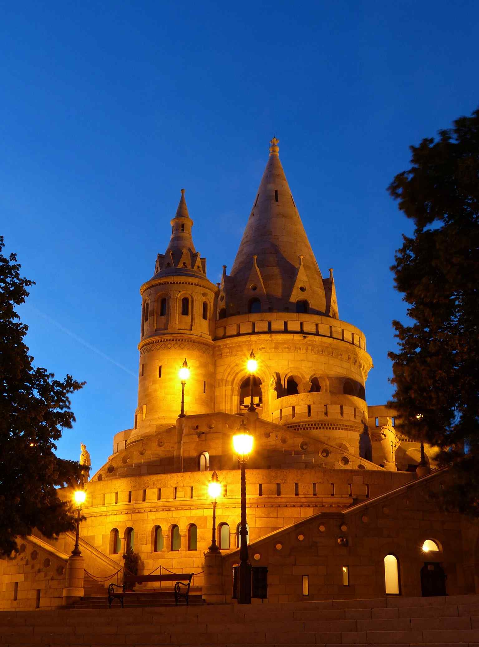 The Fisherman's Bastion glows at dusk, showcasing its Neo-Romanesque architecture and its conical roofs, symbolizing the seven chieftains of Hungary.