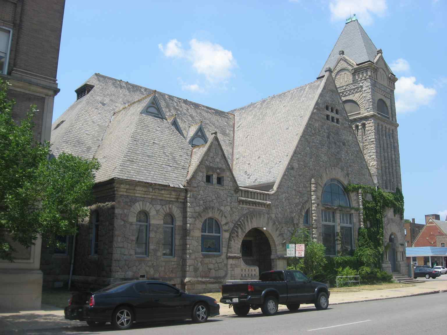 The eastern facade of the 1888 First Presbyterian Church, a Richardsonian Romanesque building, features its massive Palladian window of stained glass and a distinctive corner bell tower.