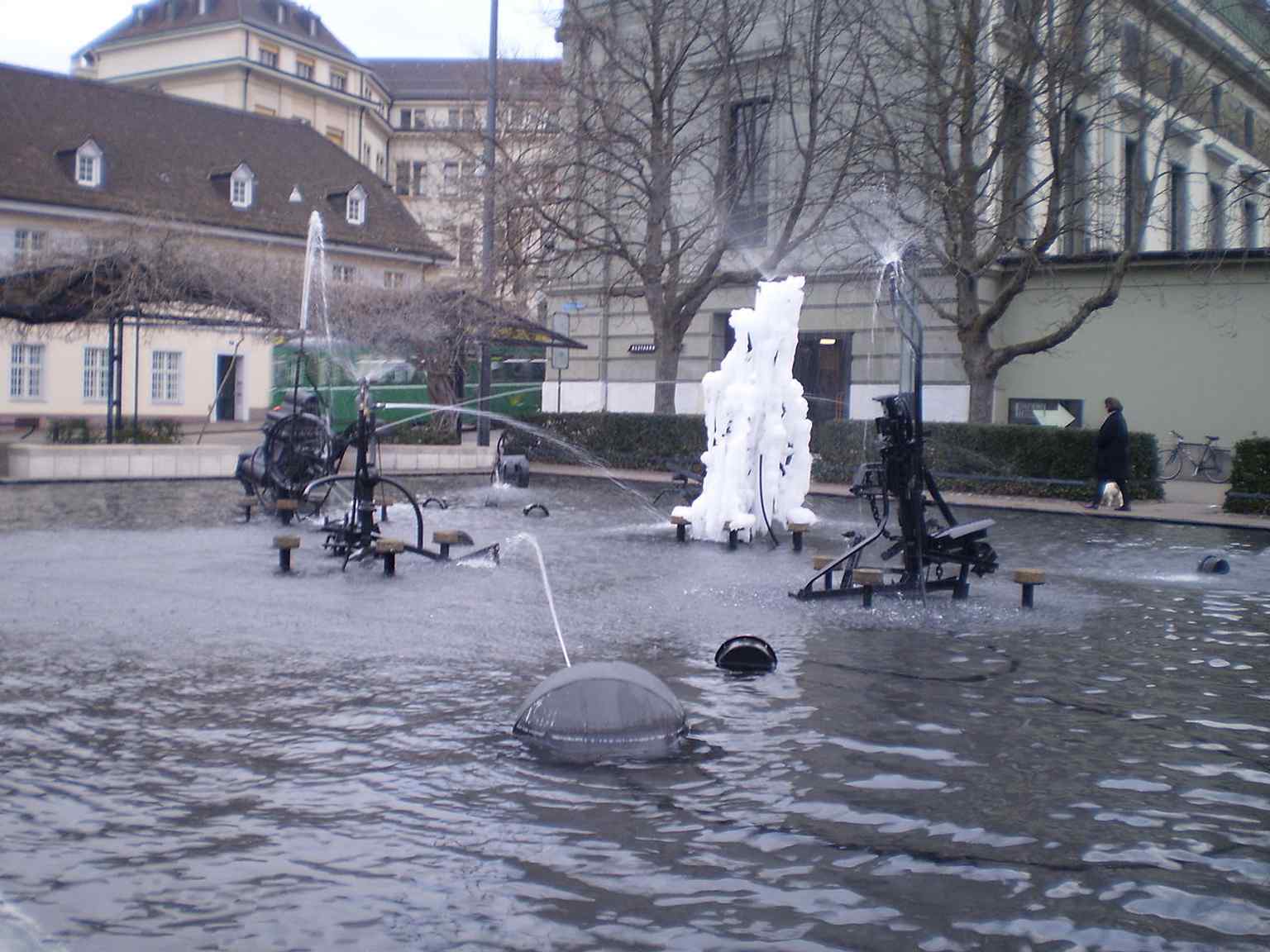 A winter scene of the fountain frozen over — a reminder that the water stays in the basin all year and must be protected from frost.