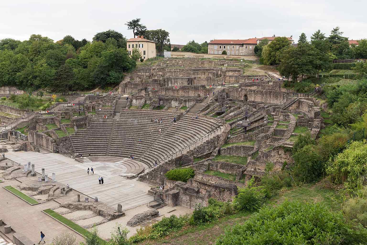 A wide overview of the ancient theatre from the Gallo-Roman museum terrace, showing how it is built into the Fourvière hillside just above Lyon.