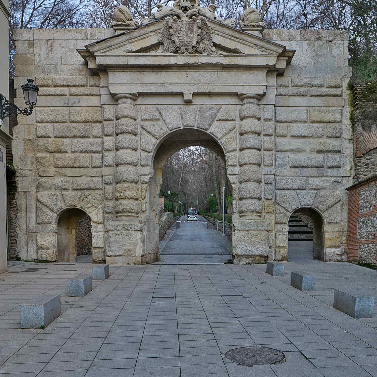 This image shows the Puerta de las Granadas, designed in the style of a Roman triumphal arch by Pedro Machuca for Emperor Charles V in 1526, featuring three pomegranates atop its main arch.
