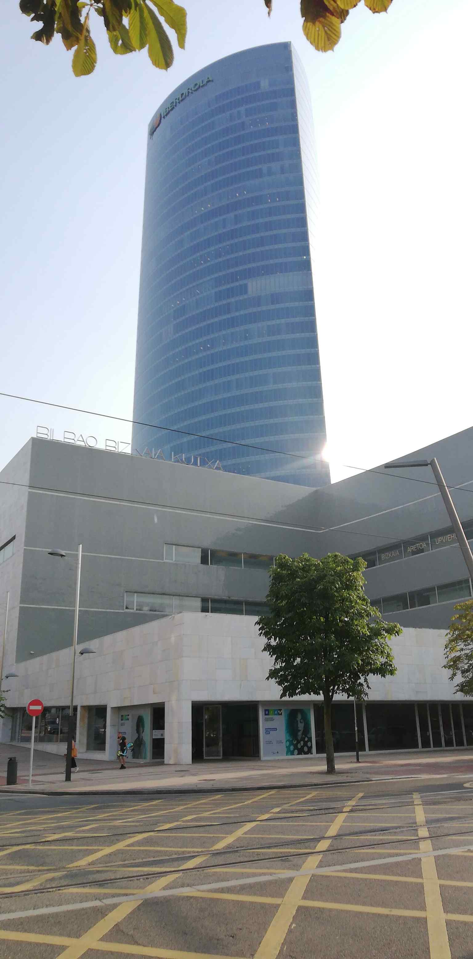 Bizkaia Aretoa’s modern façade in Abandoibarra, with the Iberdrola Tower behind it — the university’s landmark auditorium designed by Álvaro Siza.
