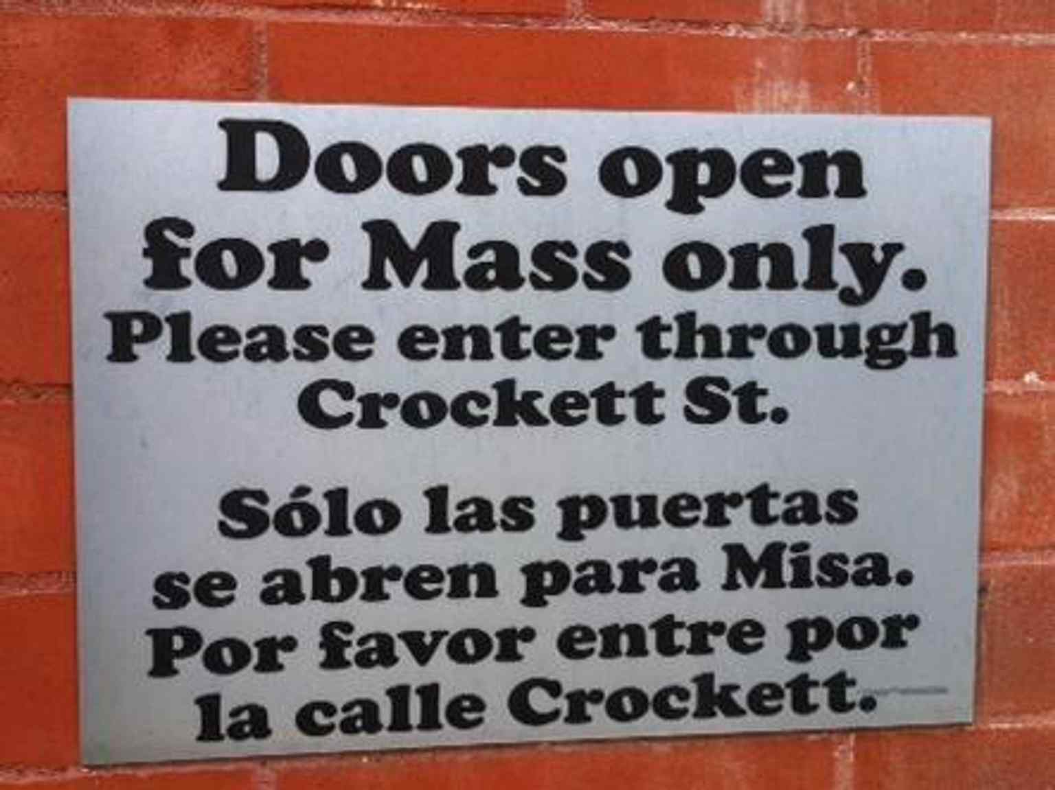 A bilingual sign showing how the cathedral serves both English- and Spanish-speaking parishioners.