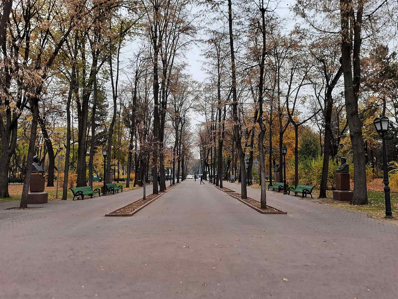 A full-length view from the fountain side, showing the tree-lined promenade where busts line both sides of the alley.