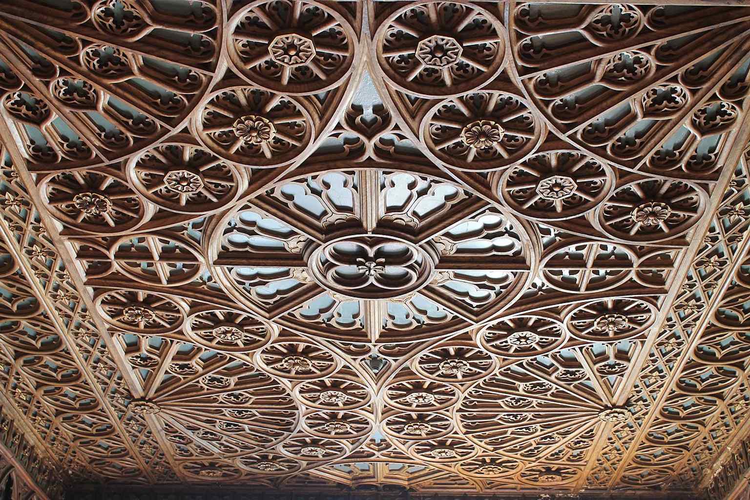 A richly carved wooden ceiling detail, showing the handcrafted artistry that gives Lello its historic, bookish atmosphere.