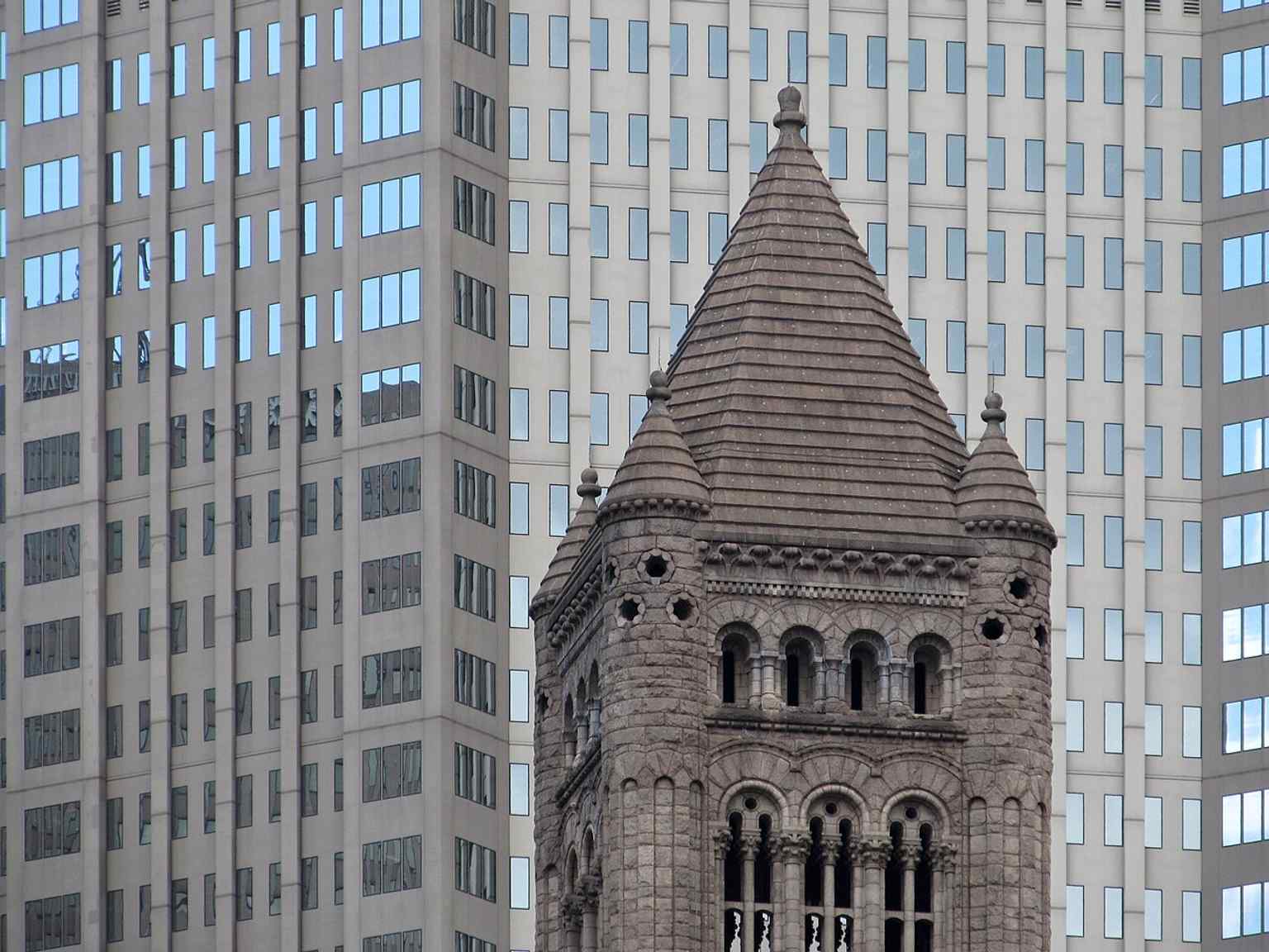 A close-up of the Allegheny County Courthouse tower, showcasing the steep roof and intricate stonework characteristic of H. H. Richardson's Romanesque Revival design.