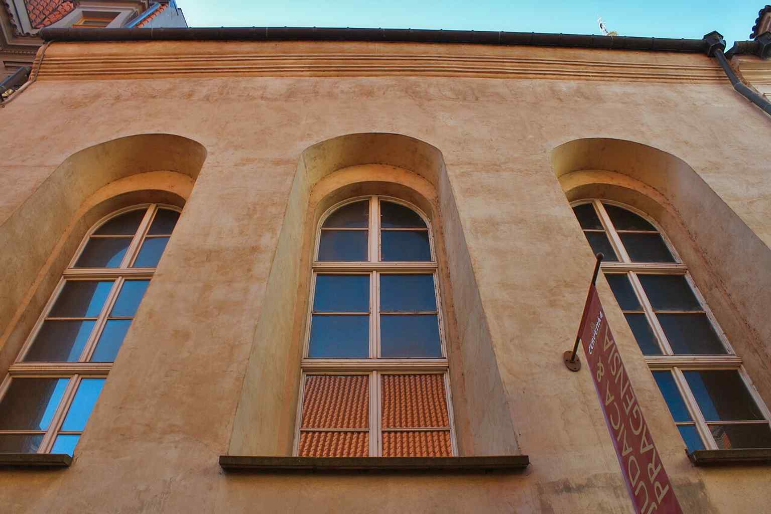 Diese hohe Außenansicht hebt die erhöhte Lage der Synagoge hervor, eine bauliche Entscheidung, die getroffen wurde, um sie vor den häufigen Überschwemmungen der Moldau zu schützen.