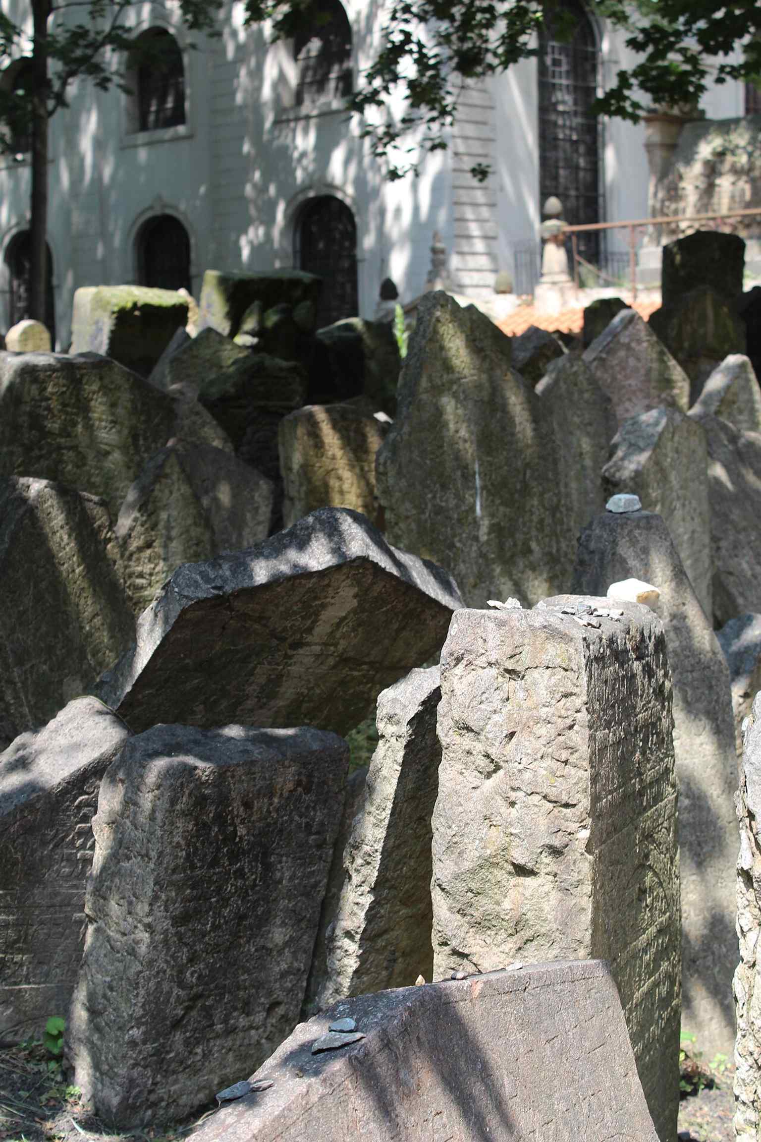 Kleine Steine, die auf einen Grabstein gelegt wurden – eine Tradition, die das Gebet oder das Gedenken eines Besuchers symbolisiert und die anhaltende Verehrung für die Verstorbenen unterstreicht.