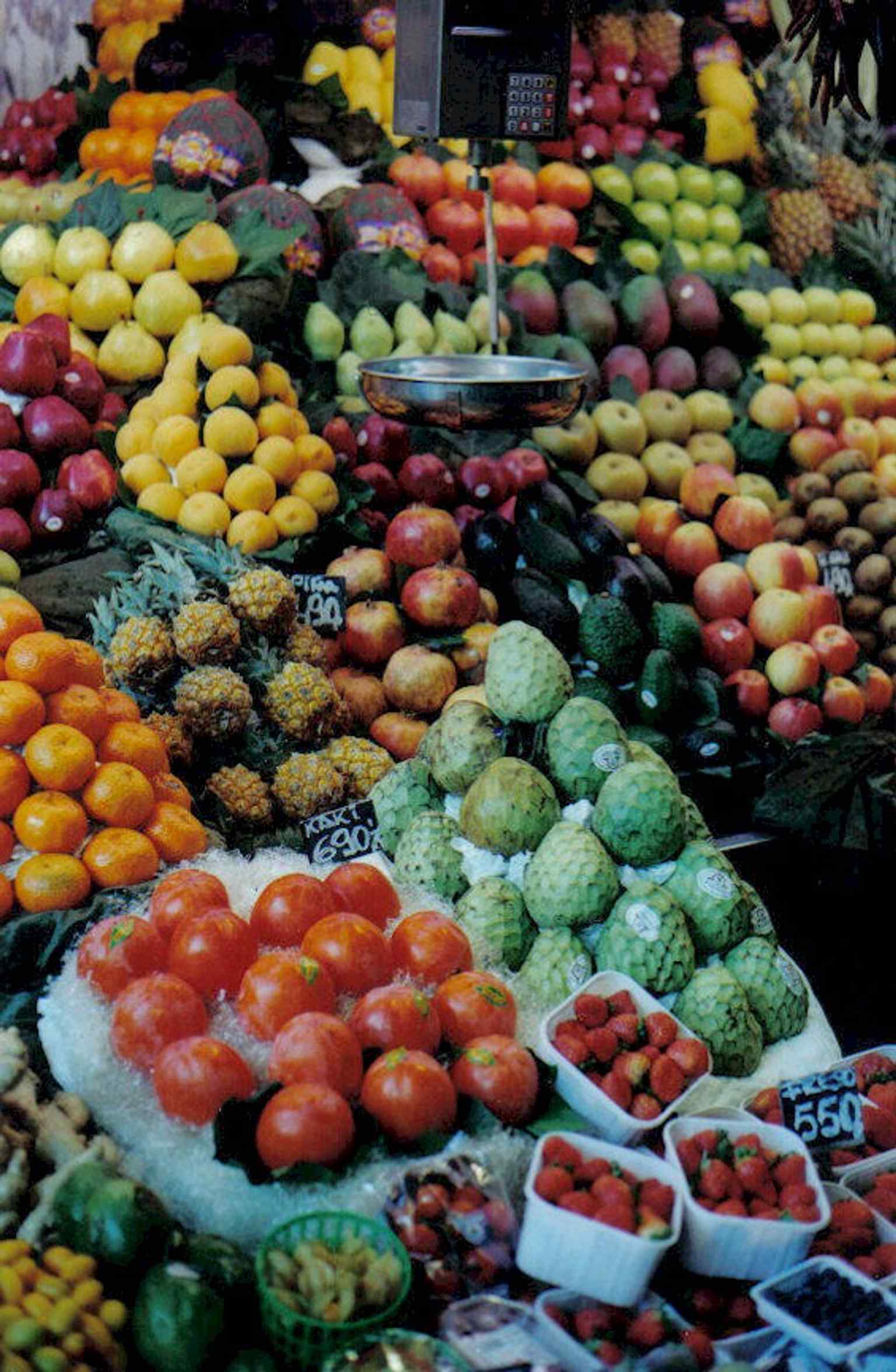 A vibrant greengrocer stall, exemplifying the deep family history of La Boqueria, where some stalls have been passed down through generations for over 150 years.