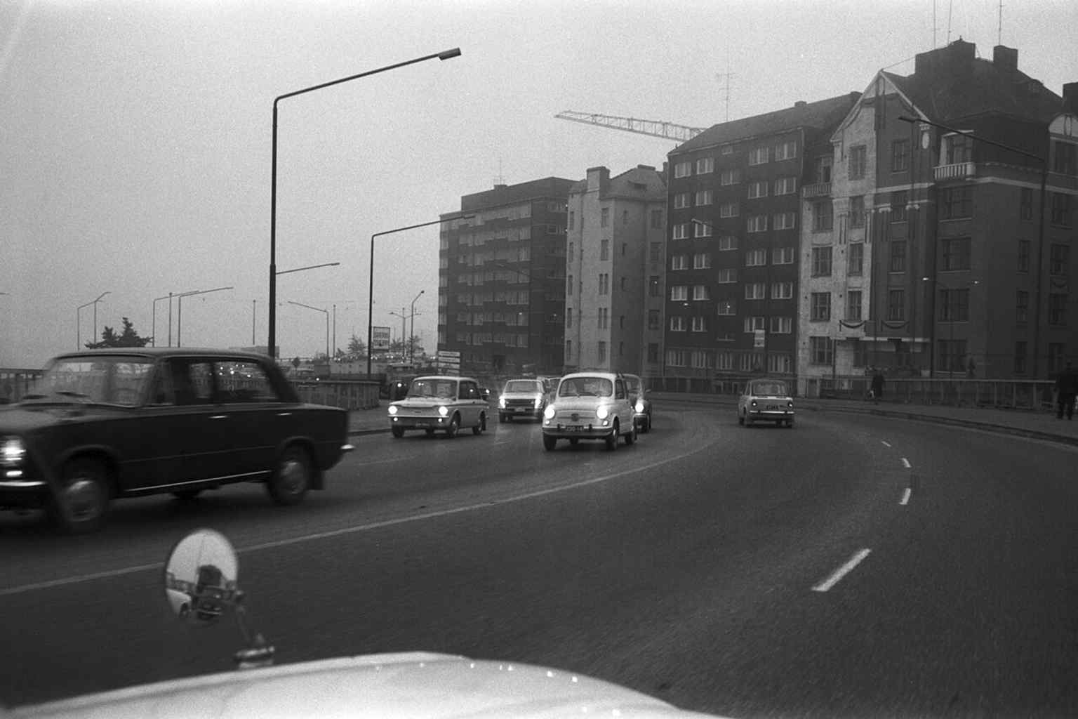 Rush-hour traffic on the old Hakaniemi Bridge in fog, with cars heading toward Kruununhaka — a reminder of how the 1961 bridge became a key route out of the Siltasaari bottleneck.