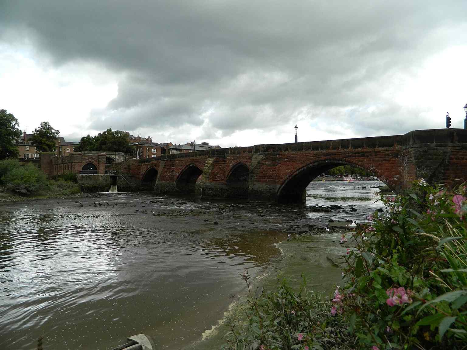 A clear side view of the bridge over the River Dee, useful for showing its red sandstone structure and multiple arches.