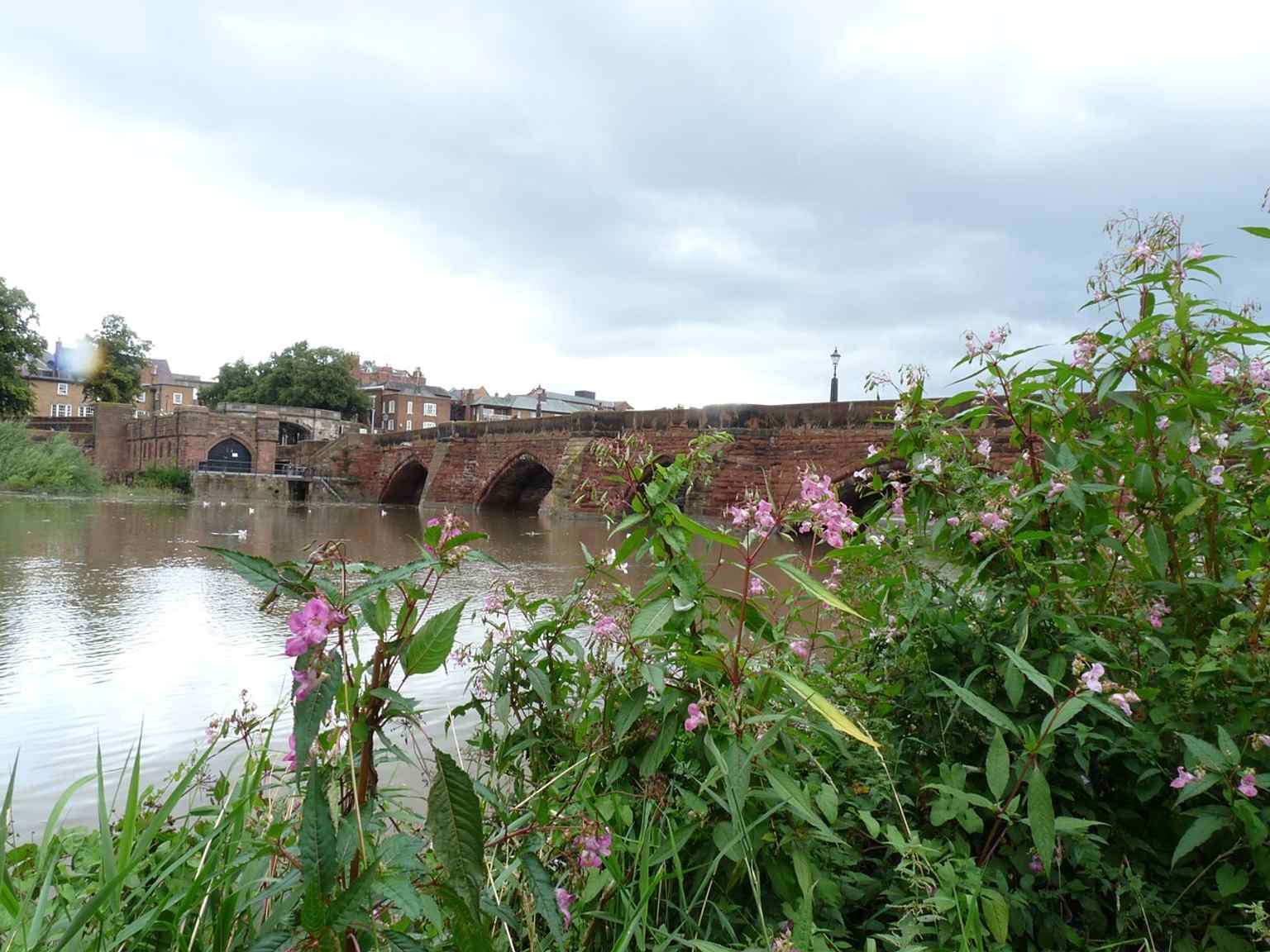 South-bank view that emphasizes the bridge’s approach over the Dee and its role as the route into Chester.