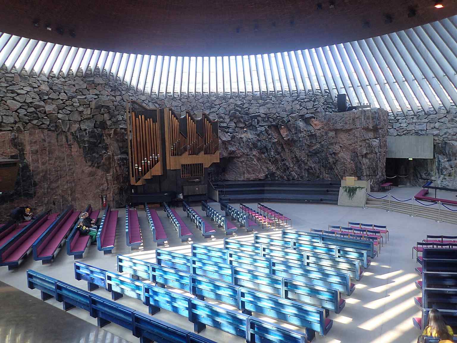 A broad interior view of the sanctuary, where rough stone walls and copper-clad surfaces create the acoustics that made the church a concert venue.