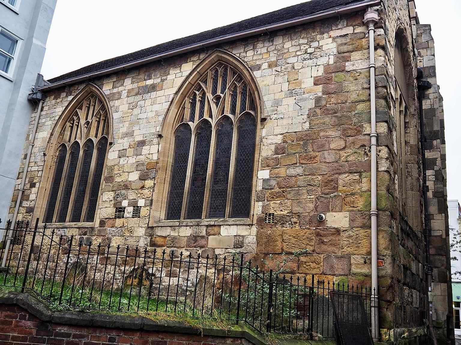 The church’s north side and churchyard show the surviving medieval building on Spurriergate, a Grade I former parish church first built in the 12th century.