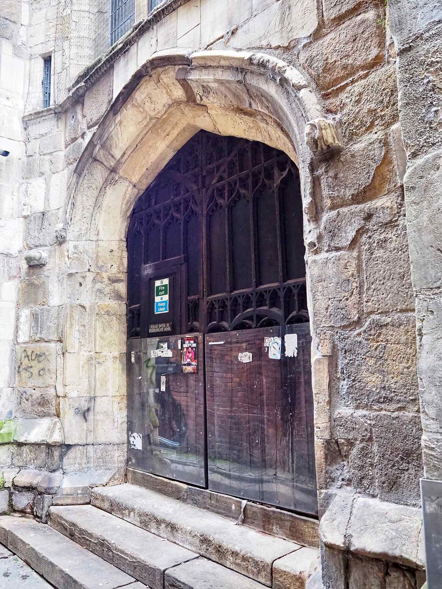 The west door preserves one of the church’s oldest exterior features, a reminder that St Michael’s still carries medieval fabric despite later street widening and rebuilding.