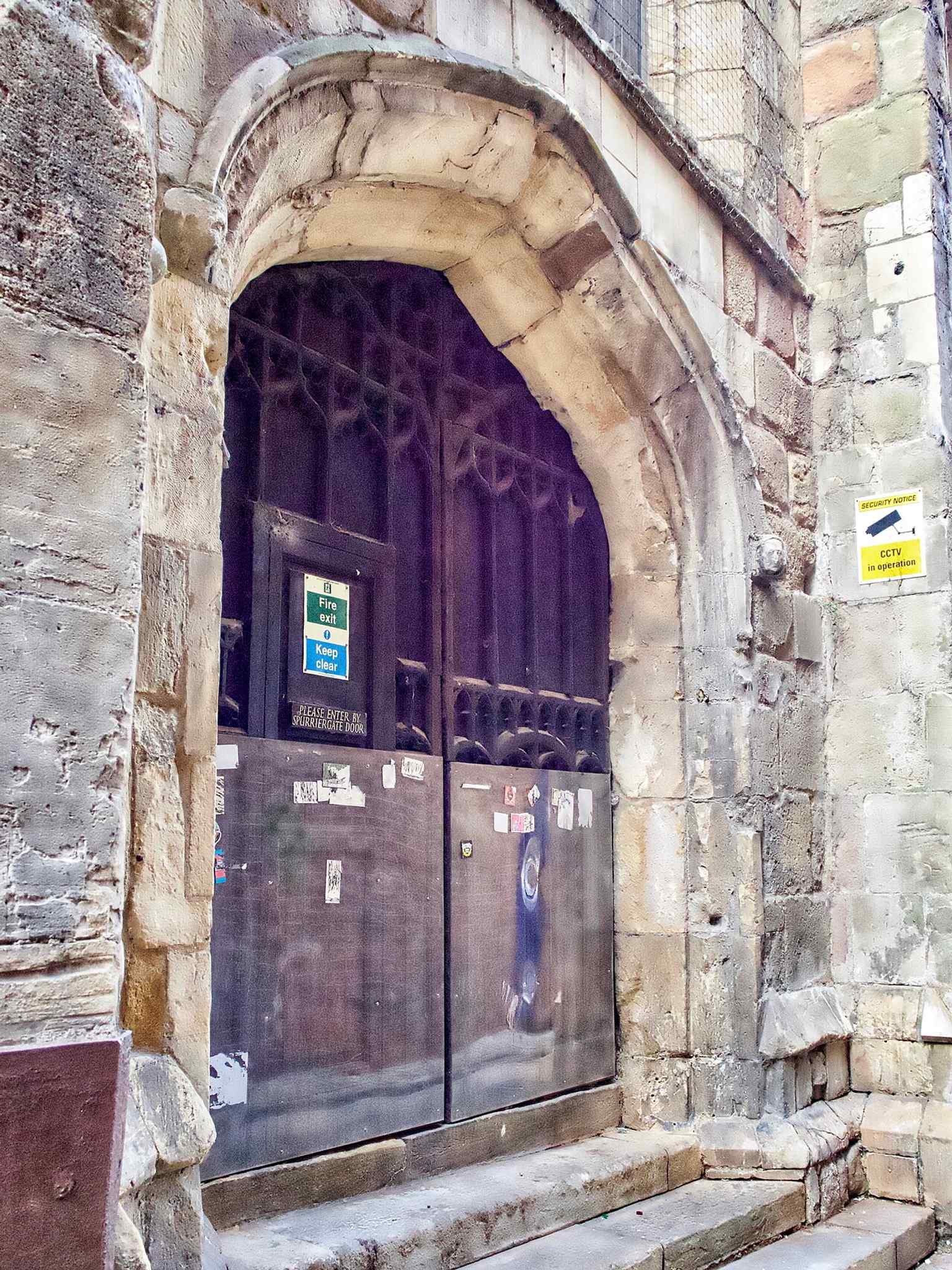 A close view of the west door highlights the church’s surviving masonry and the way the tower and front were reshaped after the lowering of the tower in the 1960s.