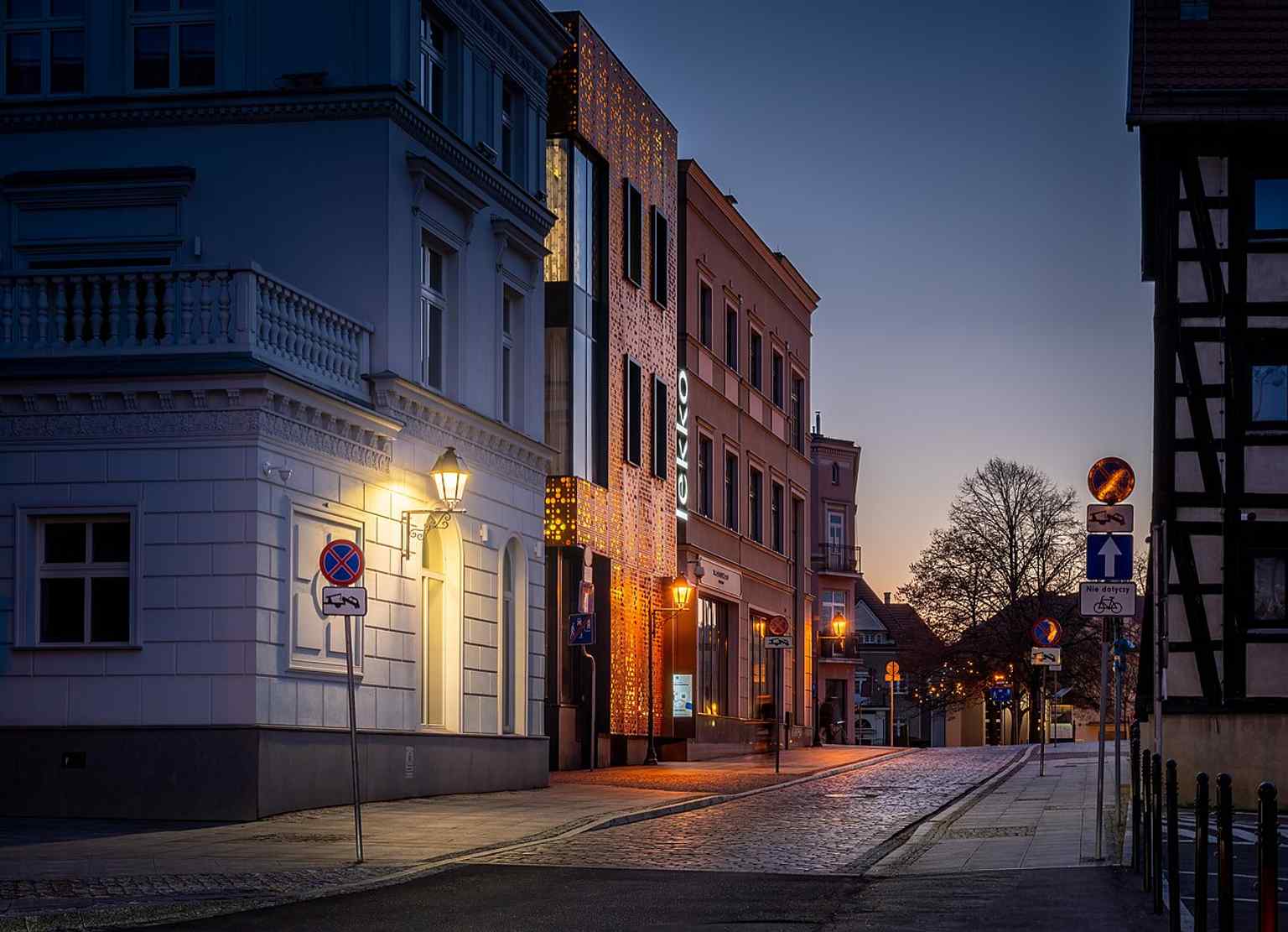 A street-level view of Grodzka Street captures the historic riverside promenade in the Old Town.