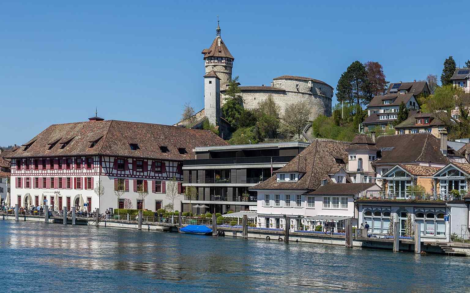 This riverside approach captures the Güterhof beside the Fischerzunft and Munot, reflecting its historic role on Schaffhausen’s Schifflände.