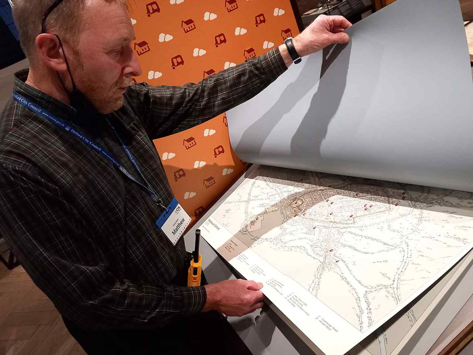 A volunteer guiding visitors through historic maps, reflecting the museum’s reliance on more than 100 volunteers.