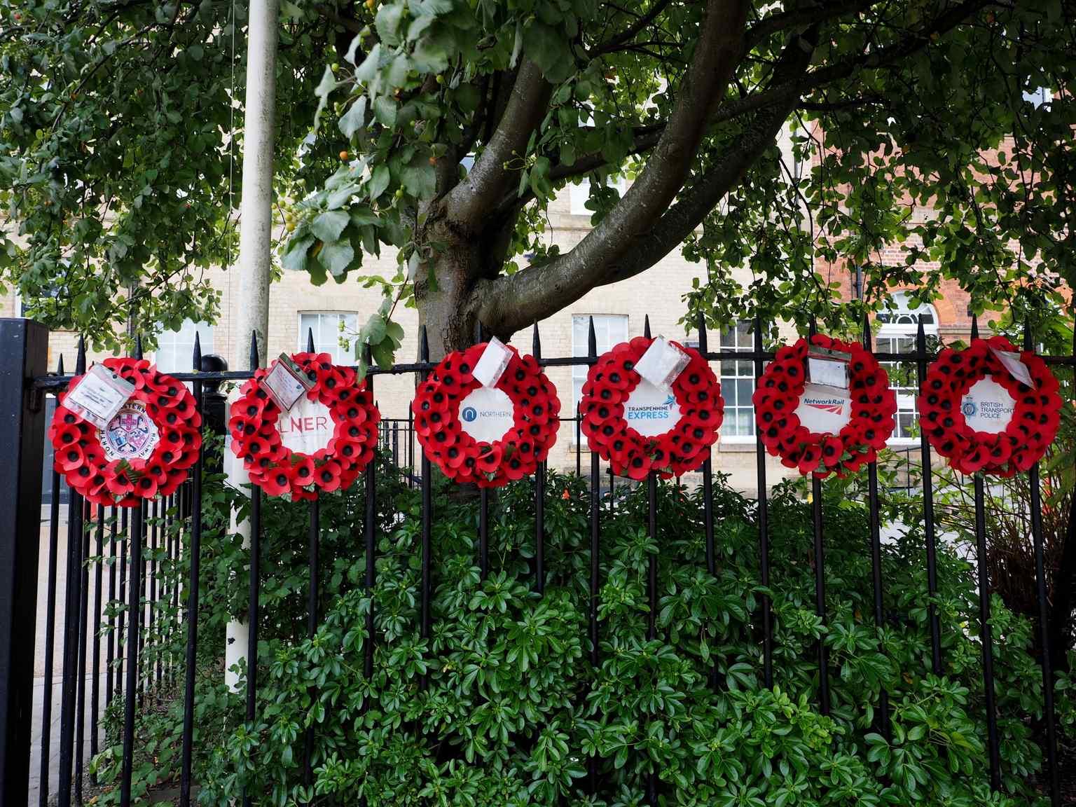 Wreaths laid by railway companies and the British Transport Police sit along the railings, honoring the enduring sacrifice and grit of the local community (2022).