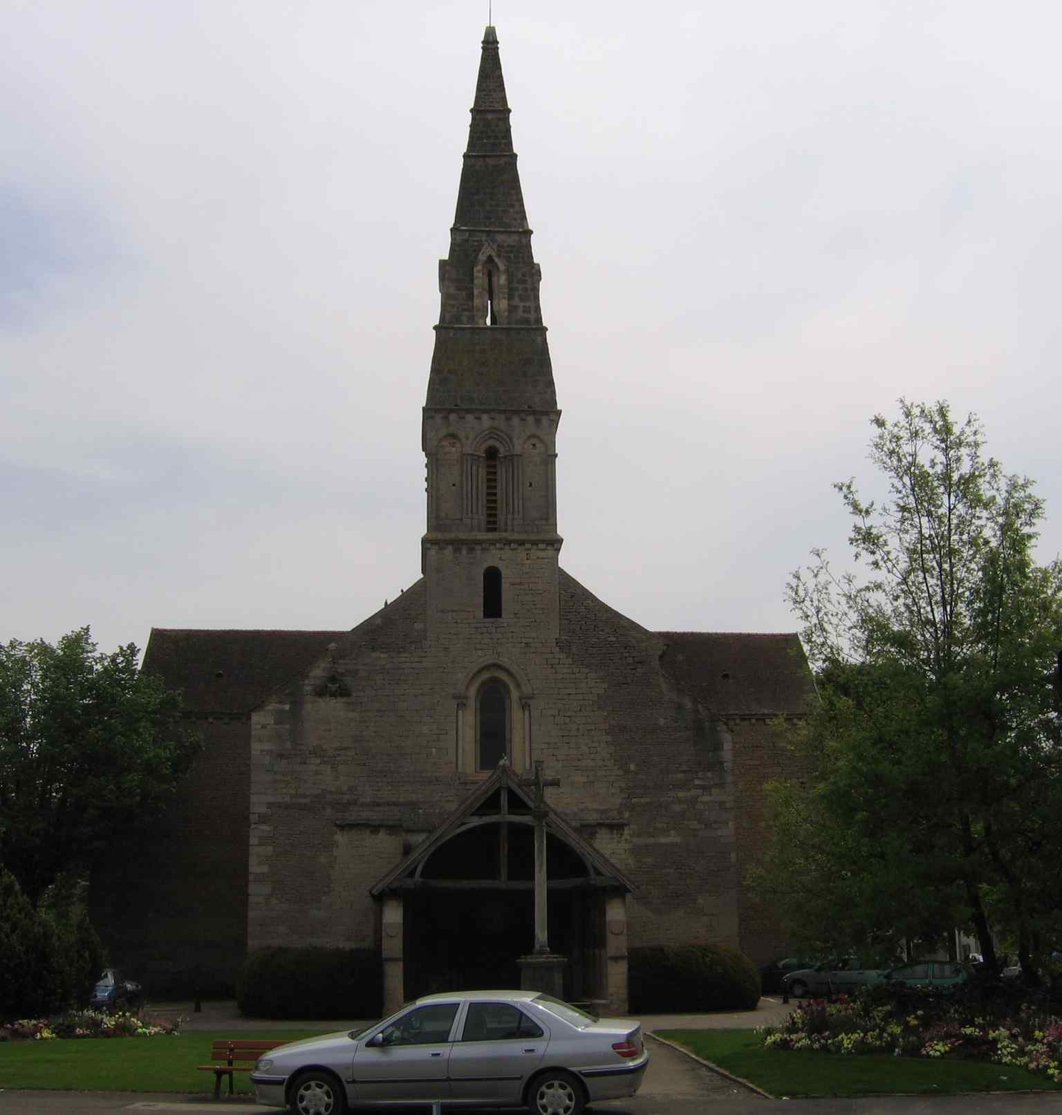 This exterior view of the Church of Saint-Nicolas highlights its distinctive 15th-century porch, whose timber frame is adorned with carved chimeras and engouled beams, echoing details found in Beaune's famous Hôtel-Dieu.