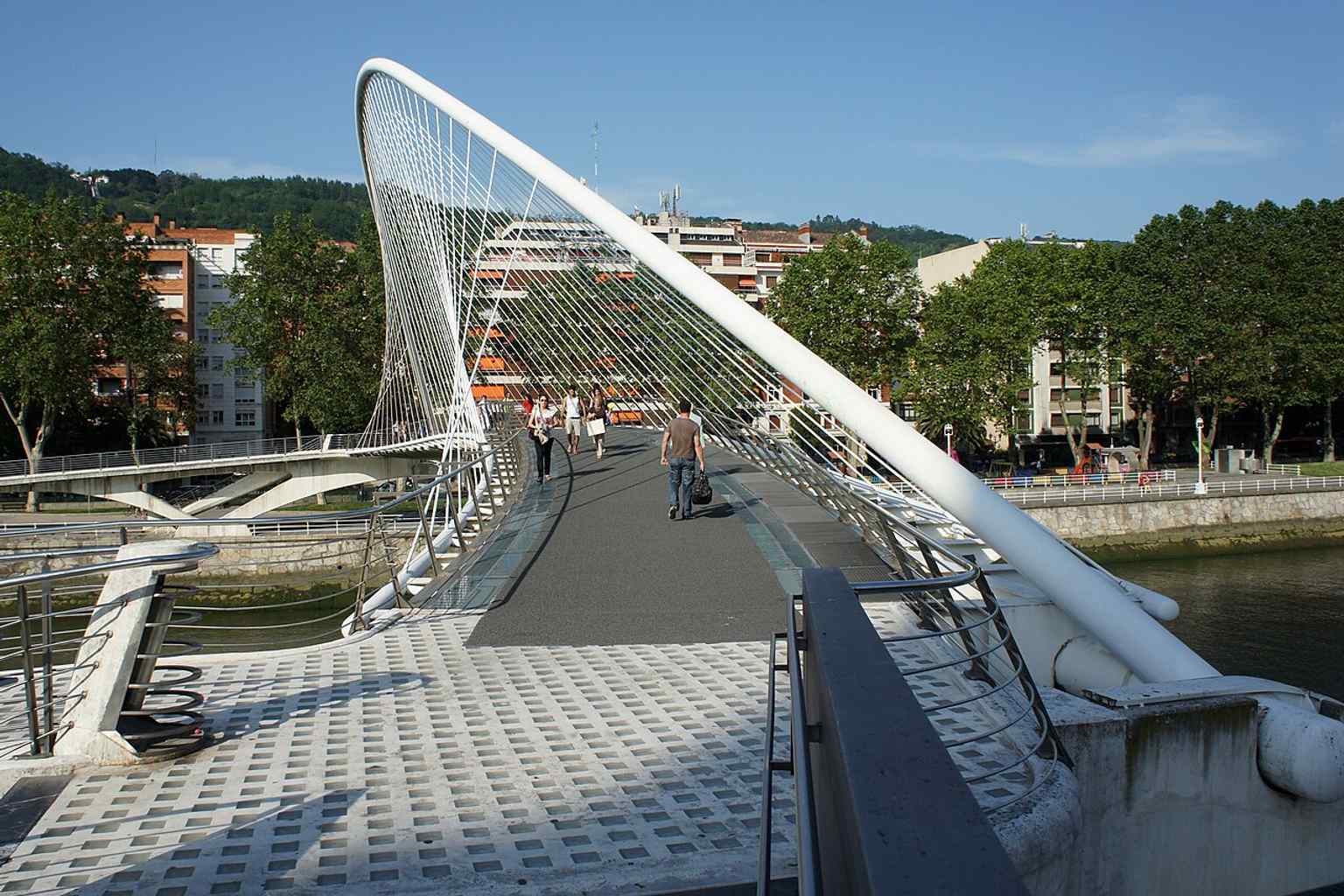 The white bridge seen across the water, reflecting the clean, minimalist look associated with Calatrava’s Bilbao projects.