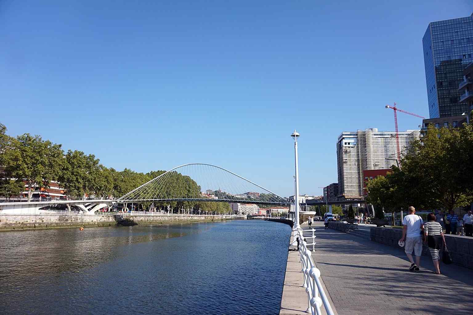 The bridge approached along the river walkway, matching the popular paseo route from Campo Volantín toward the Guggenheim area.