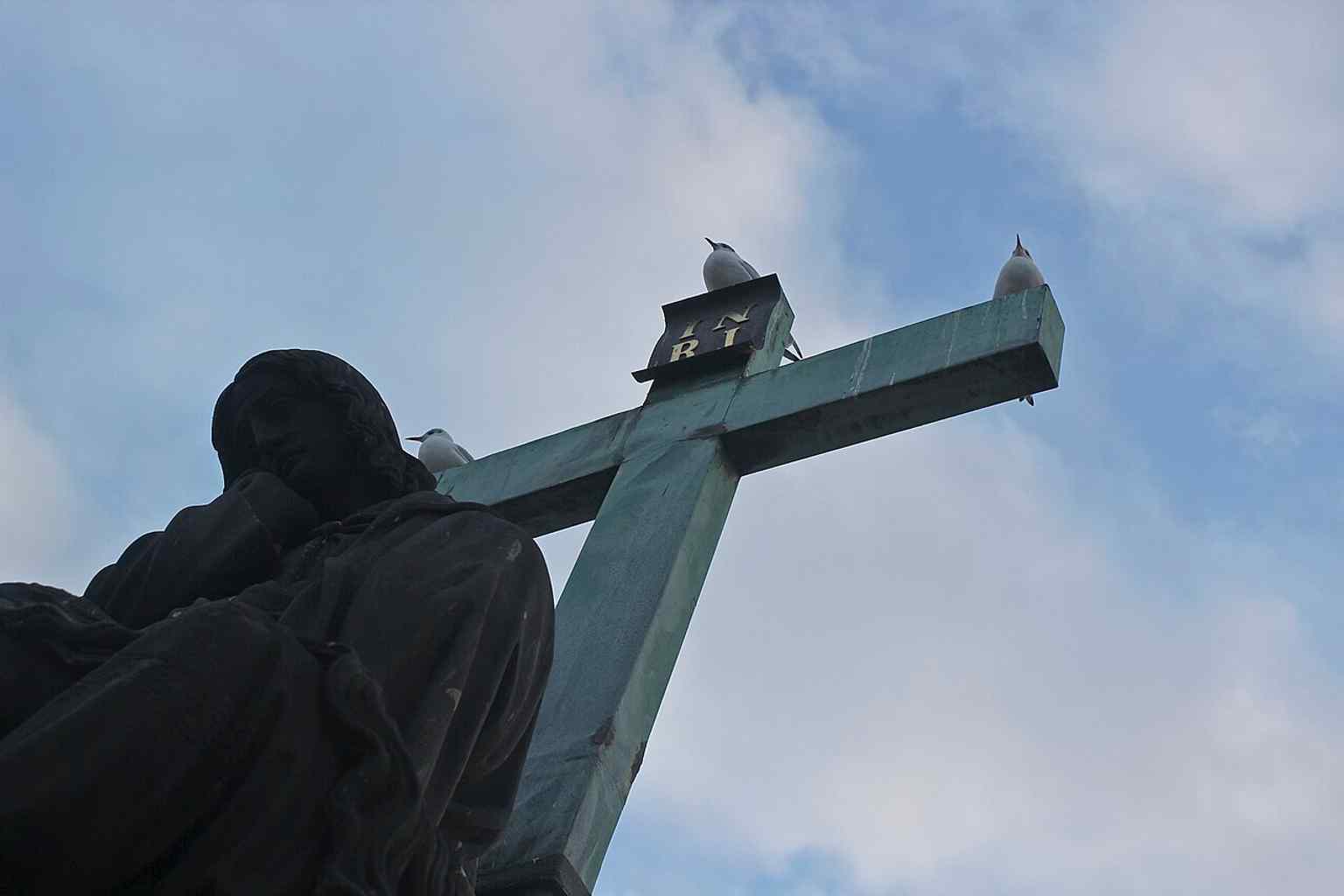 The Pietà statue stands resiliently on Charles Bridge, here seen amidst snowy conditions, reflecting its history of surviving natural elements and historical events.