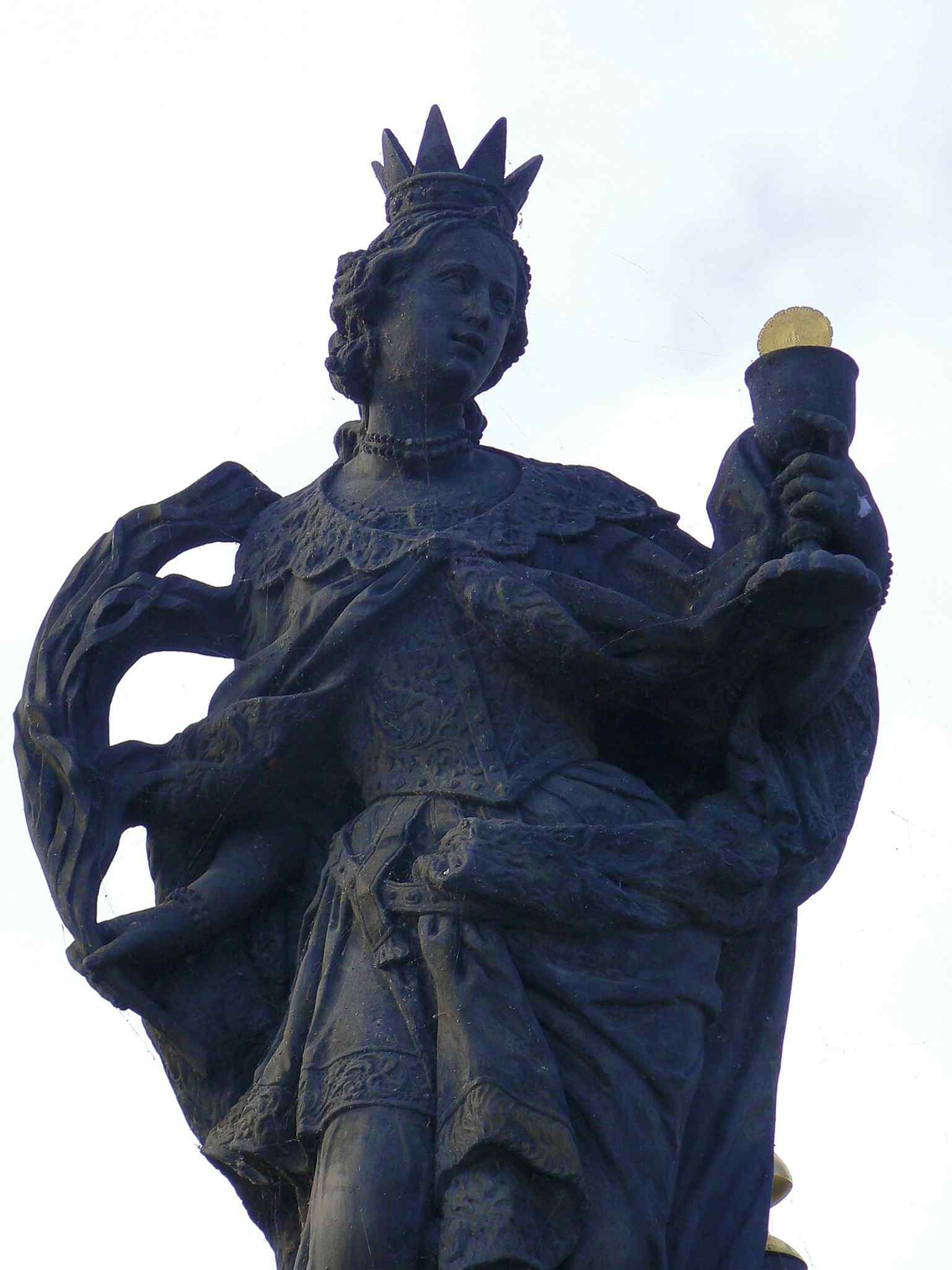 A close-up of Saint Barbara holding a chalice with a gilded host, symbolizing the final sacrament, with a miniature tower at her feet representing her imprisonment.