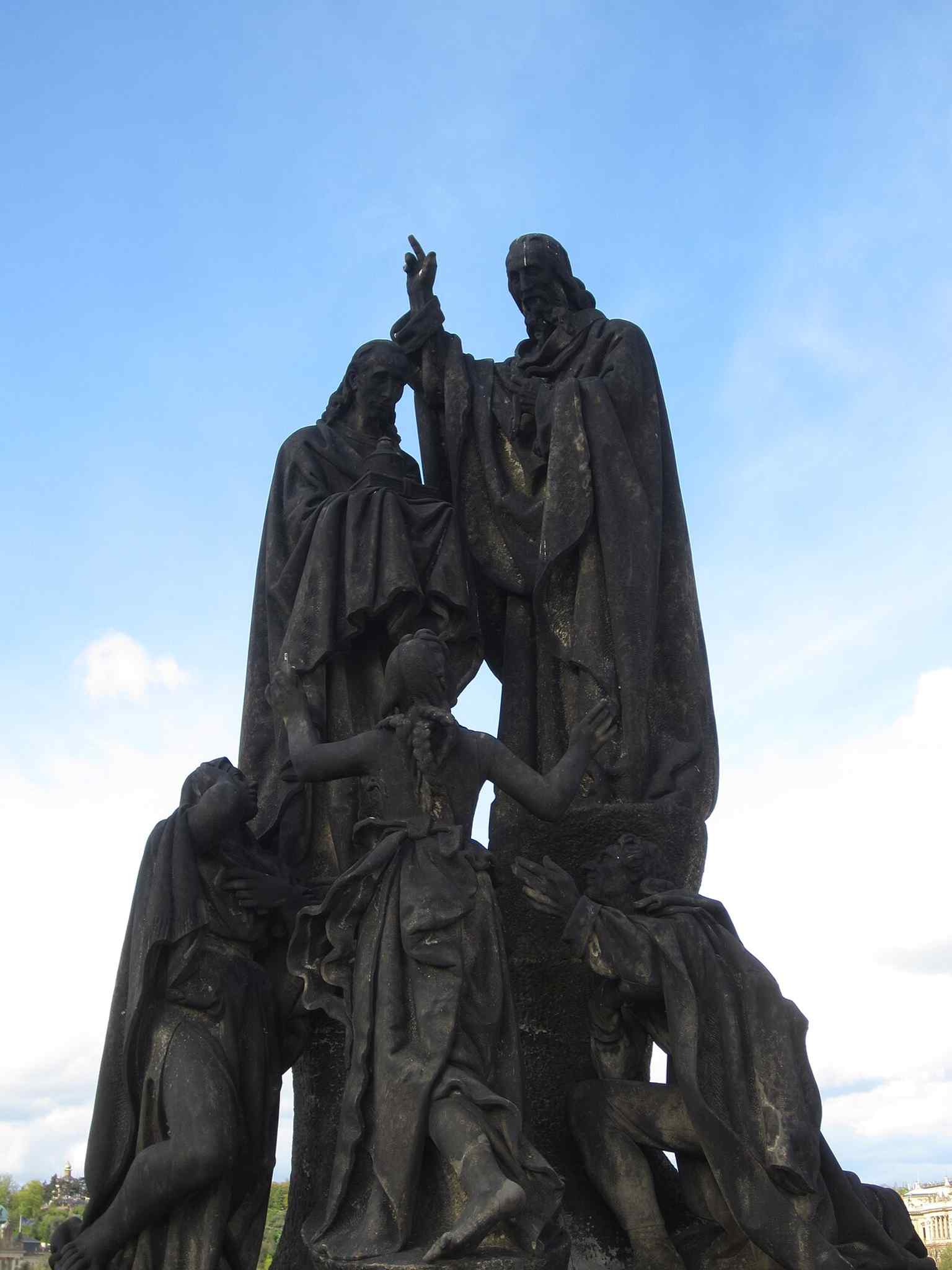 The monumental Saints Cyril and Methodius sculpture, standing prominently on the north side of the Charles Bridge, overlooking the Vltava River.