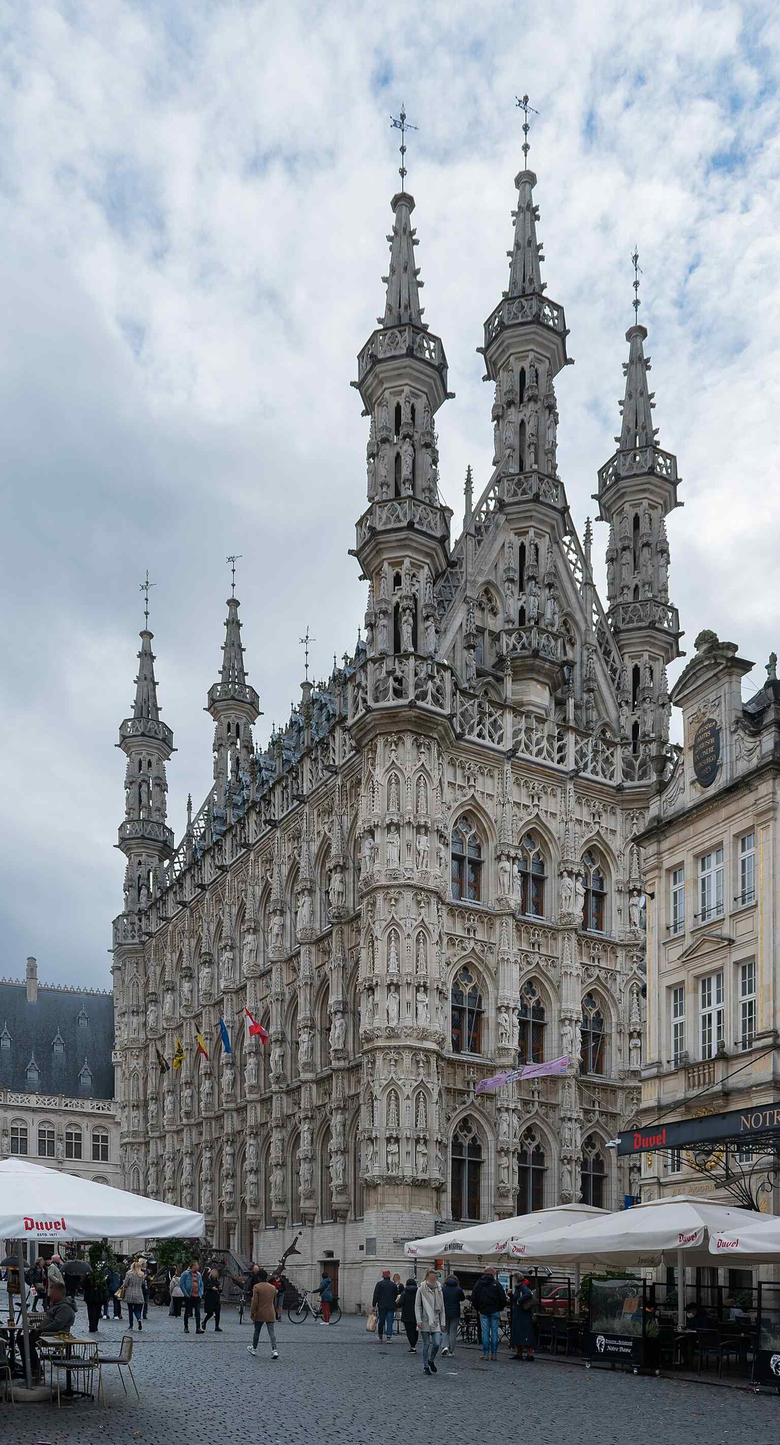 A full-height view of the Town Hall, emphasizing the steep roof and clustered turrets that replaced the original plan for a heavy corner belfry.