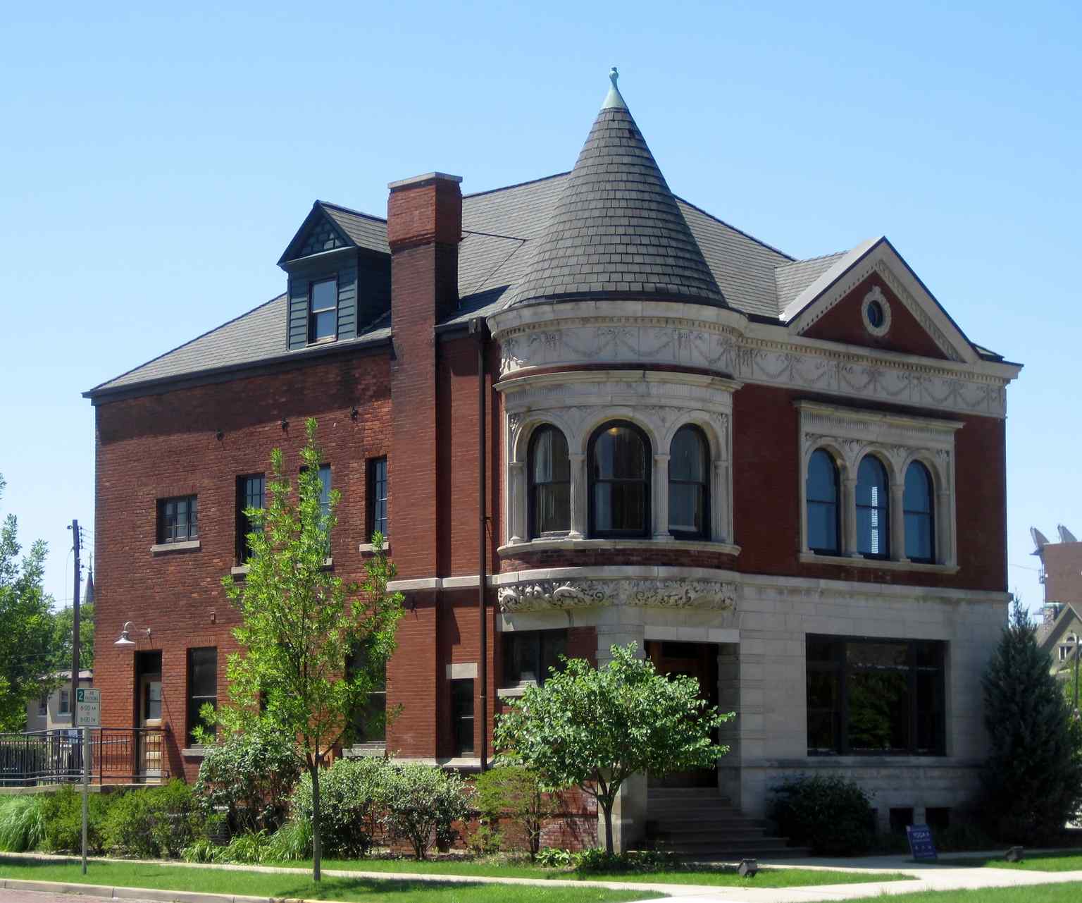 The South Bend Remedy Company Building, constructed in 1895, uniquely disguised itself as an elegant private home despite its commercial purpose, featuring a distinctive round turret and wide frieze band.