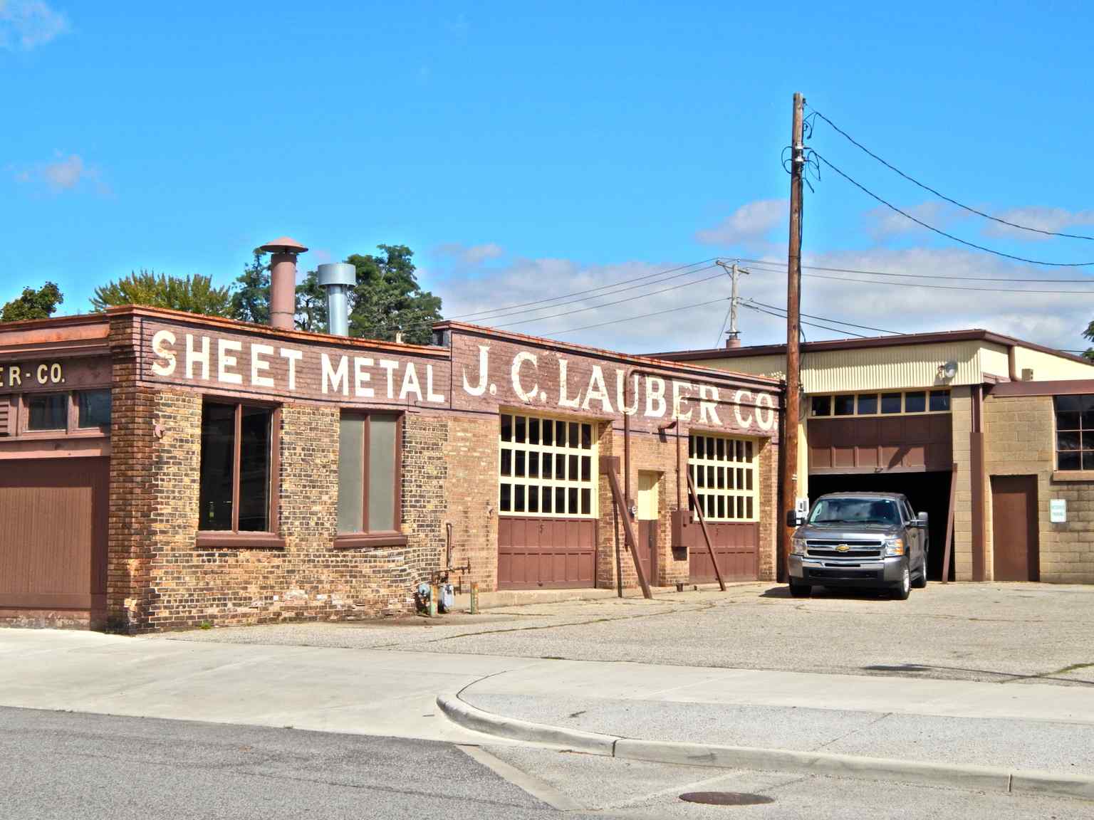 Observe the historic brickwork on the building's south wall, part of the complex that housed the J. C. Lauber Sheet Metal Company for 125 years.