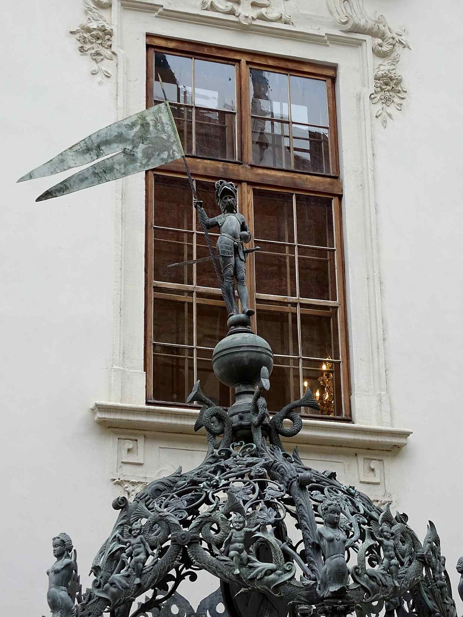 A close-up of the armored figure atop the courtyard fountain, echoing the source’s description of the fountain laurel crowned by a warrior.